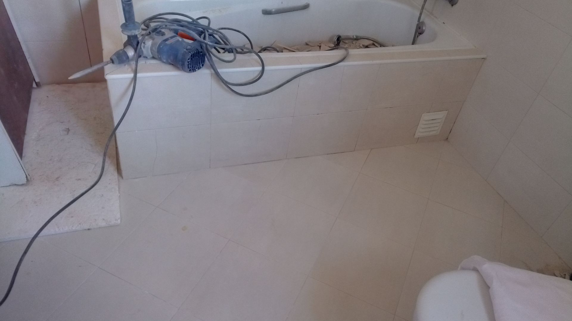Banheiro em construção; instalação de drywall ao redor da banheira, perfuração e piso novo.