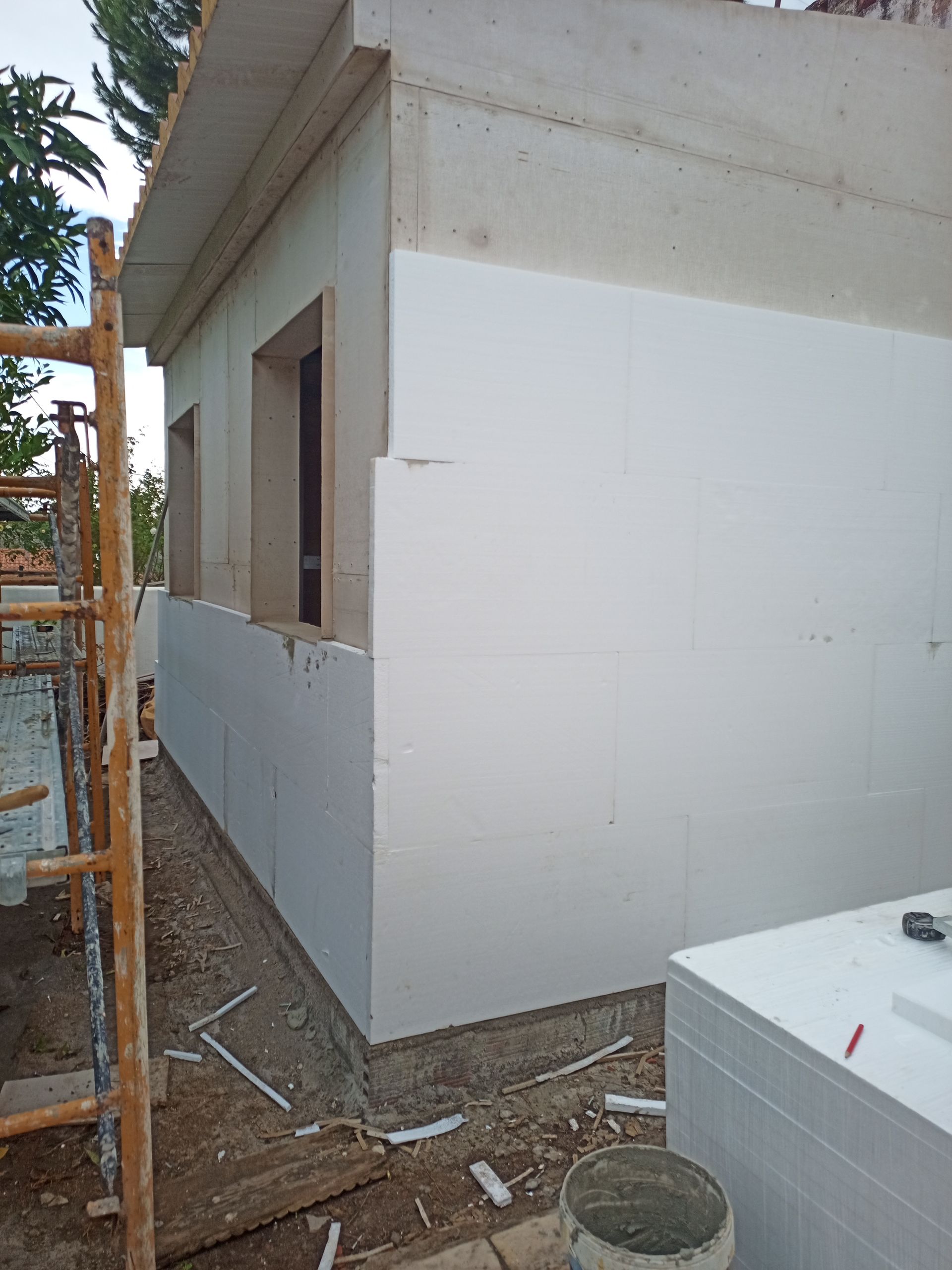 Exterior de um edifício em construção, com painéis de isolamento de espuma branca instalados nas paredes.