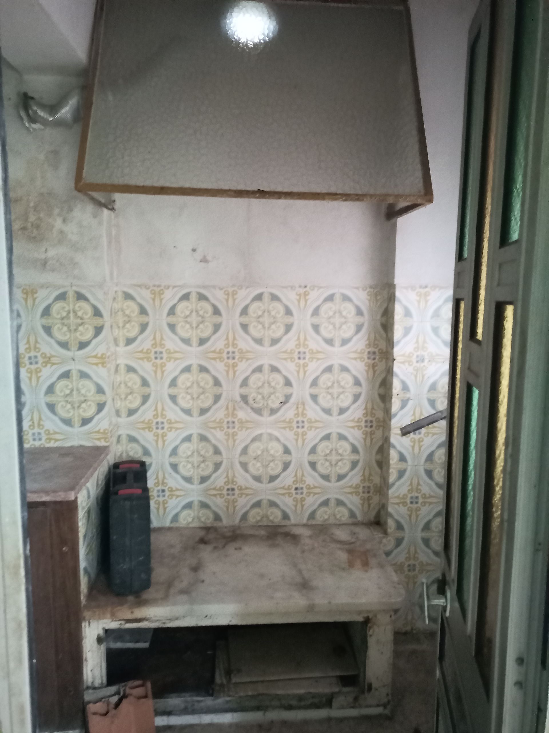 Cozinha pequena com backsplash de azulejos, bancada de concreto e coifa.