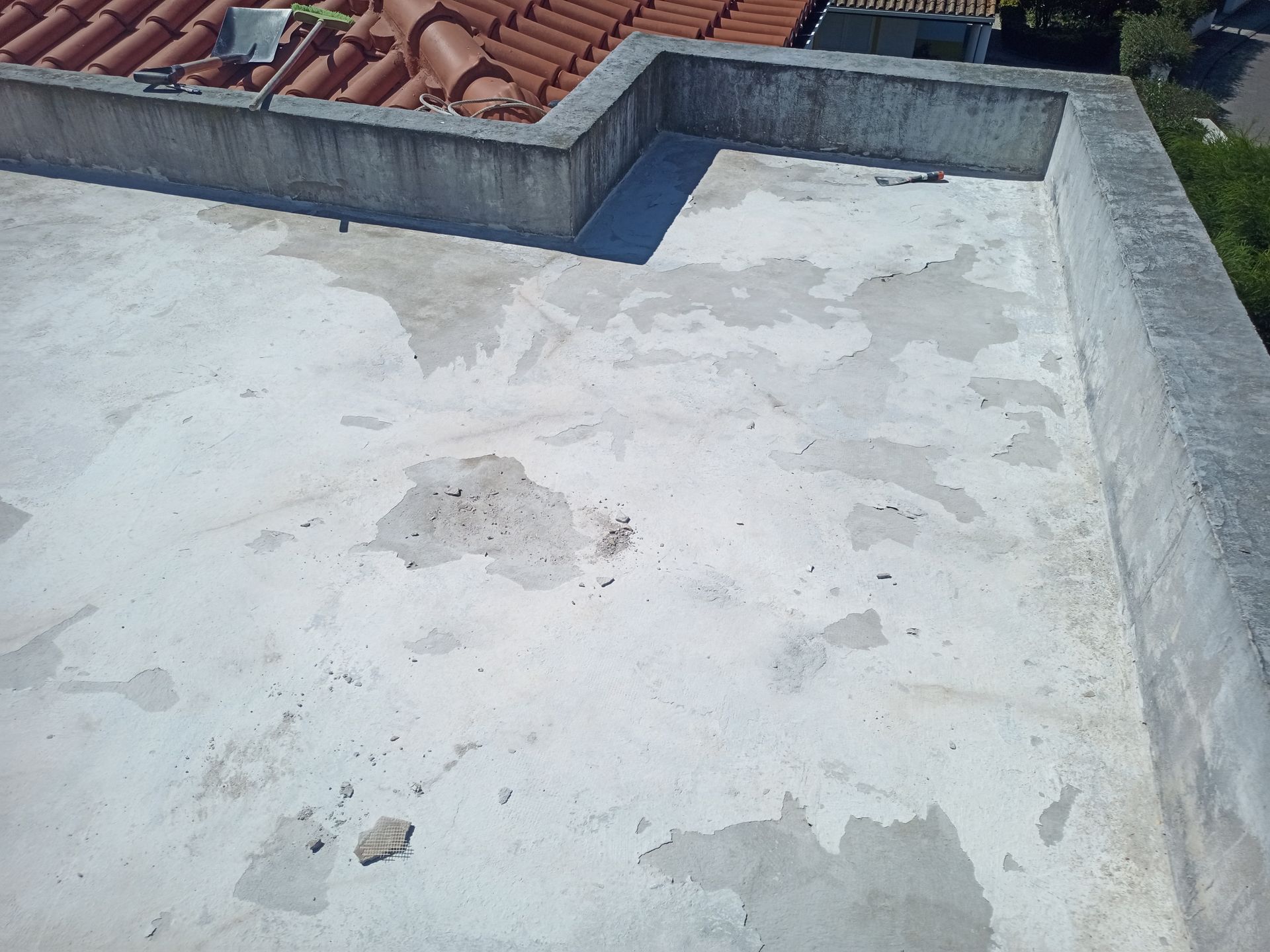 Telhado plano de concreto com tinta descascando e bordas de concreto.