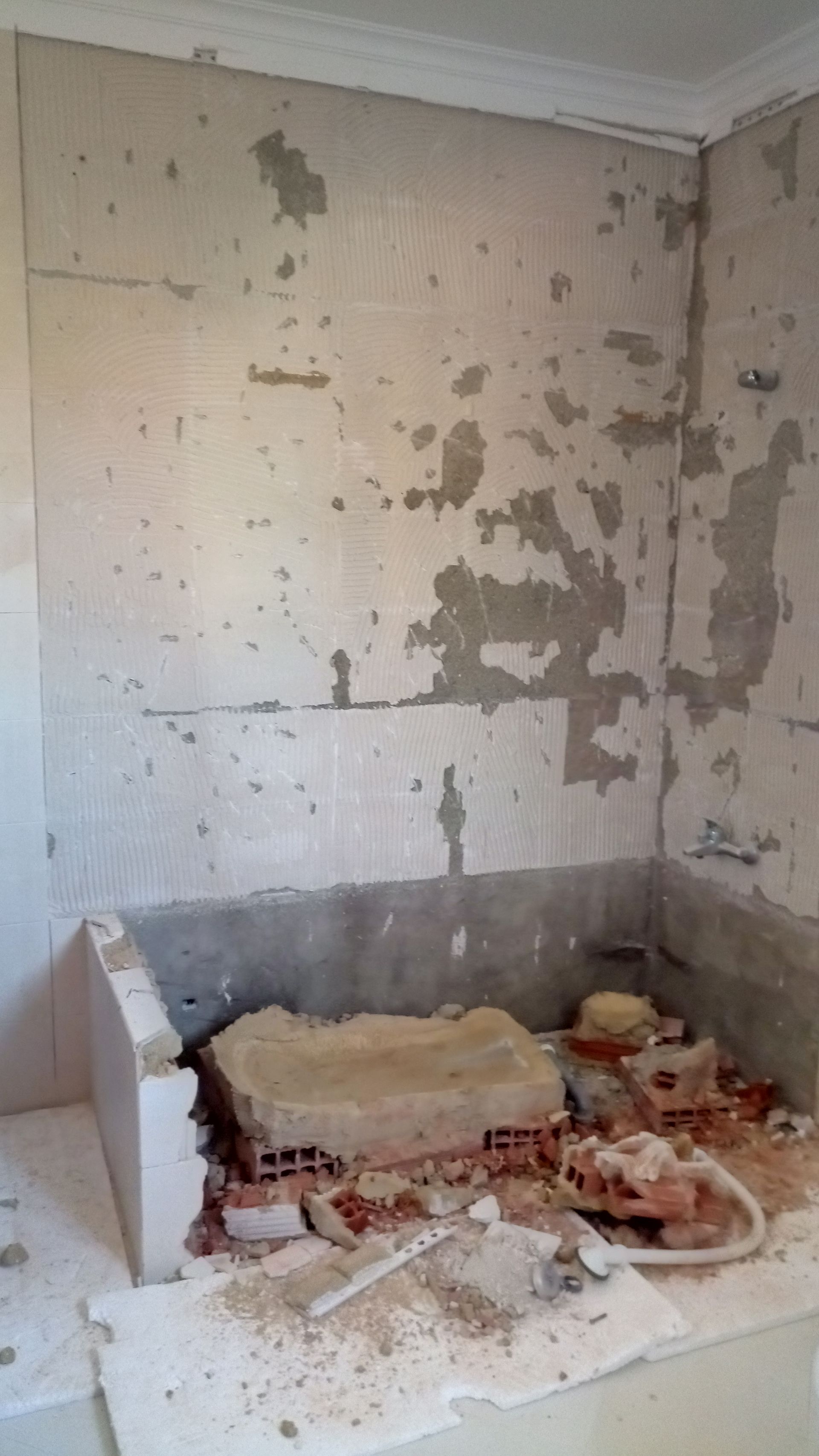 Canteiro de obras: tijolos aparentes, parede remendada, entulho em uma prateleira, moldura branca.