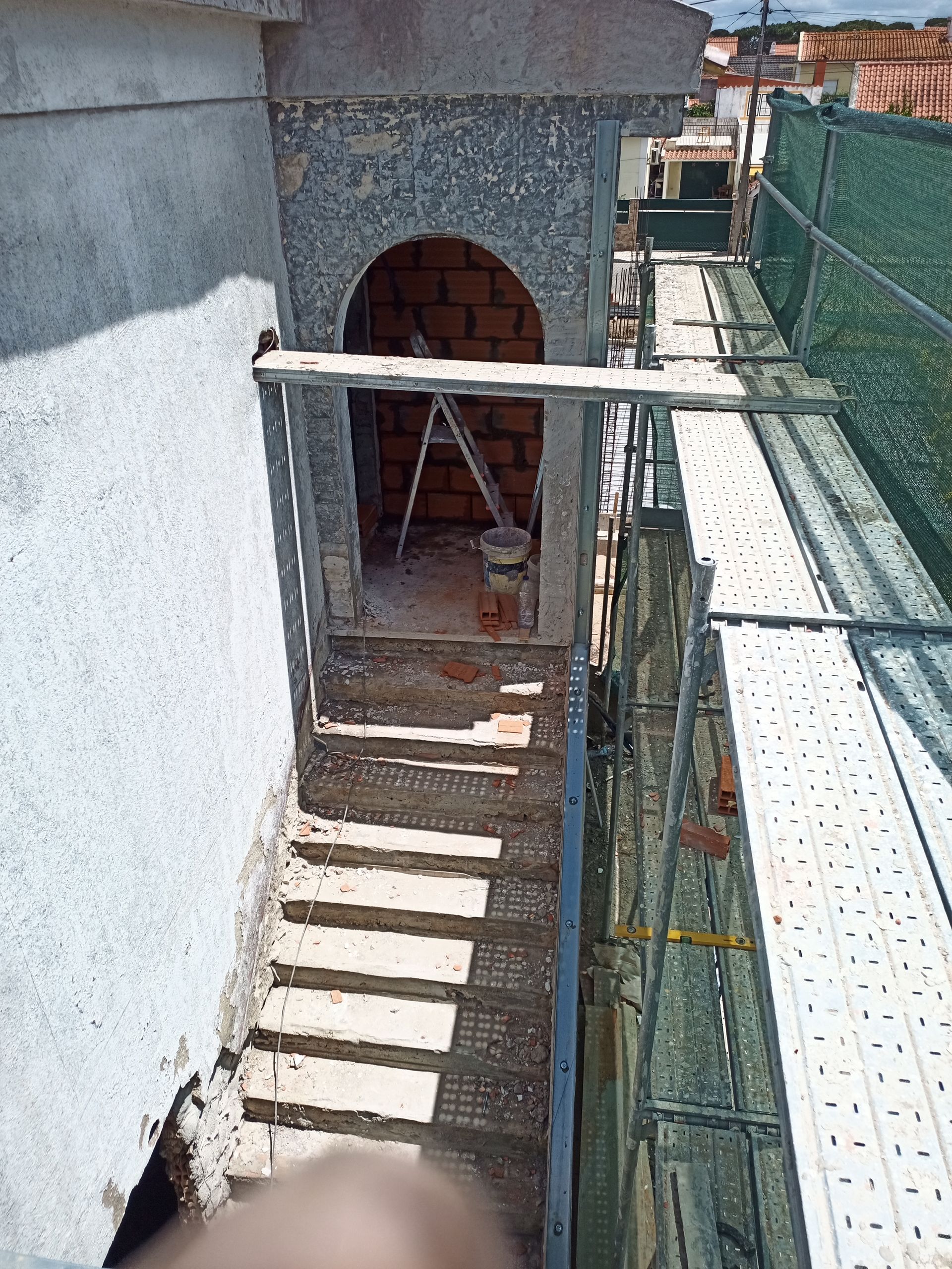 Canteiro de obras: Porta de tijolos, degraus externos, andaimes.