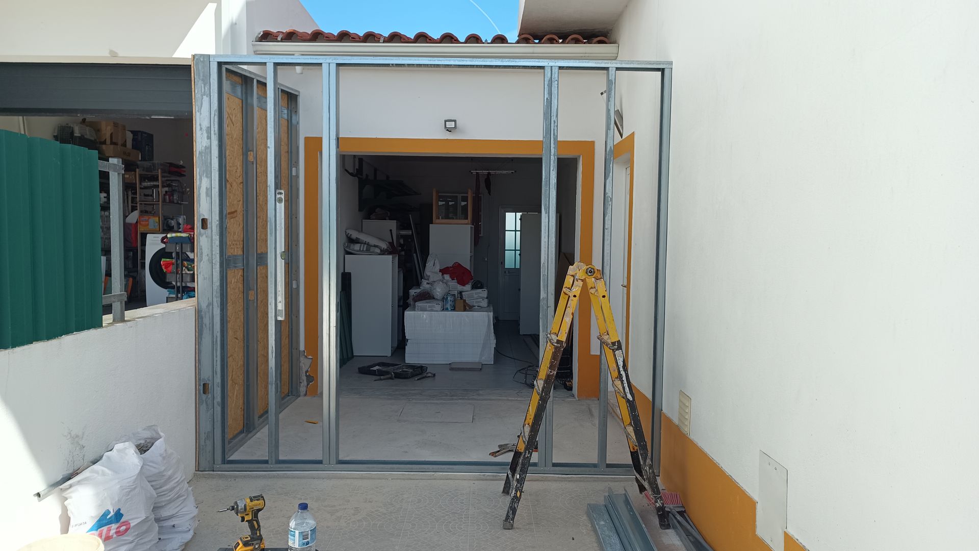 Estrutura metálica para uma porta em construção, com vista para um cômodo e uma escada presente.