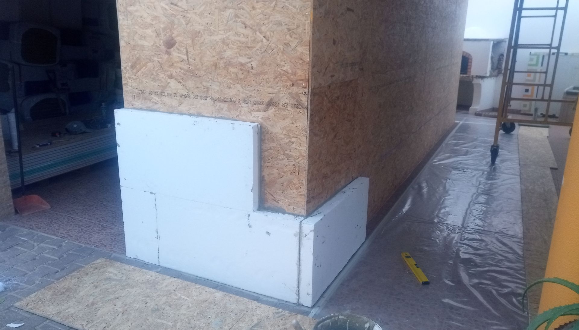 Parede de canto com painéis isolantes sendo instalados. Construção em madeira OSB com isolamento de espuma branca no exterior.