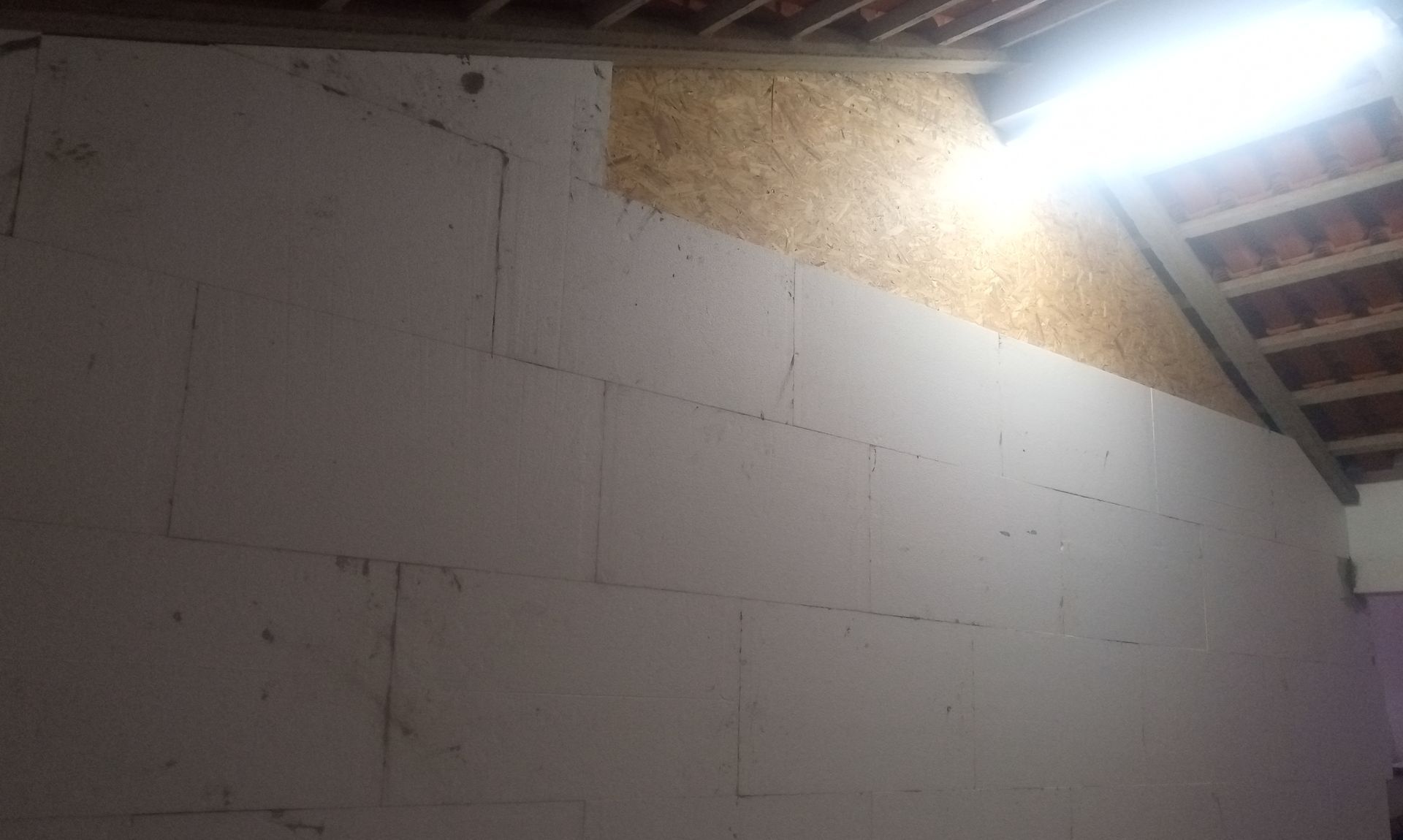 Vista interior de uma parede com blocos brancos e um painel de madeira clara.