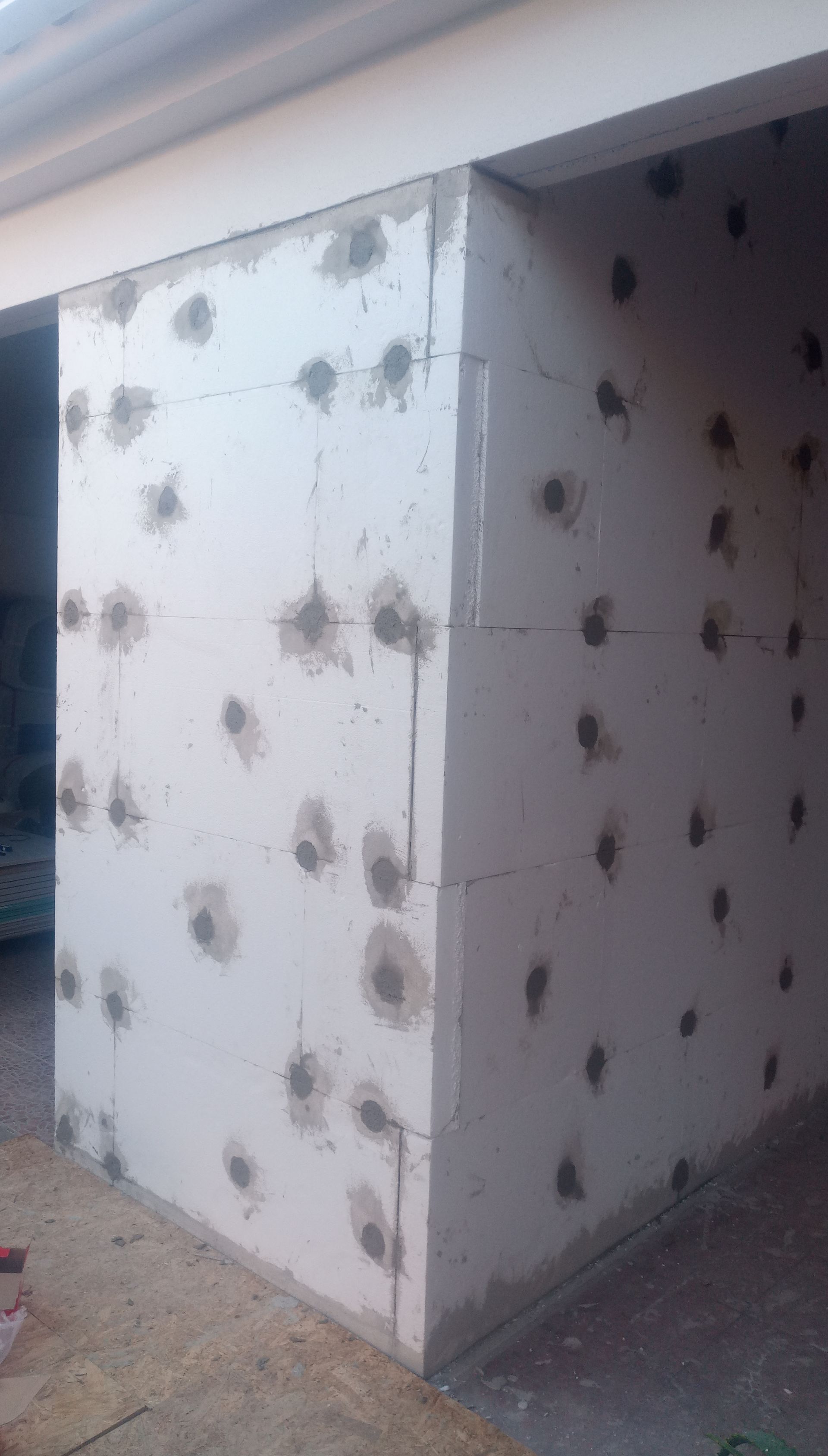 Parede de blocos de espuma branca com inúmeras manchas de concreto cinza.