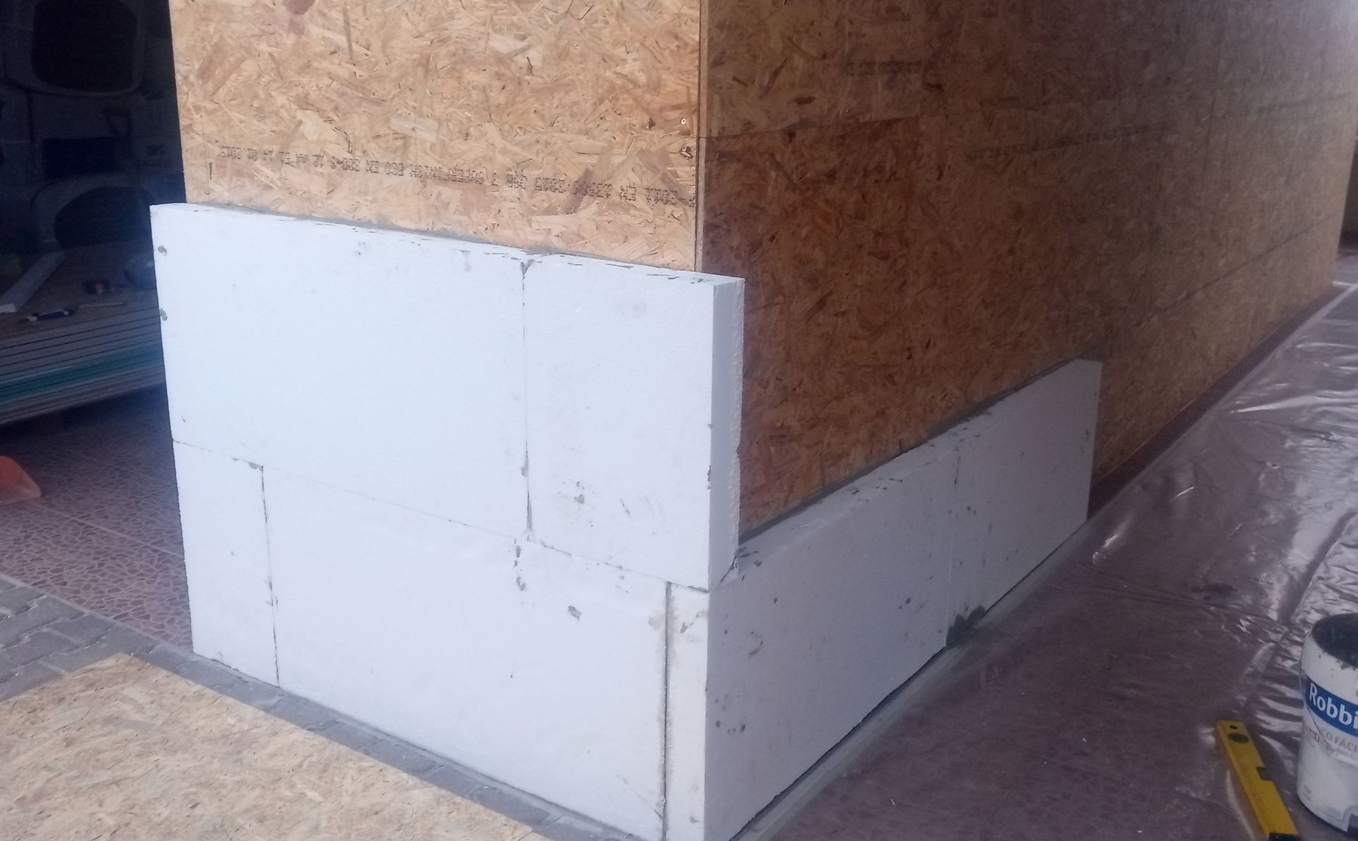 Isolamento de espuma branca fixado em uma parede com painéis de madeira, no canto de um prédio em construção.