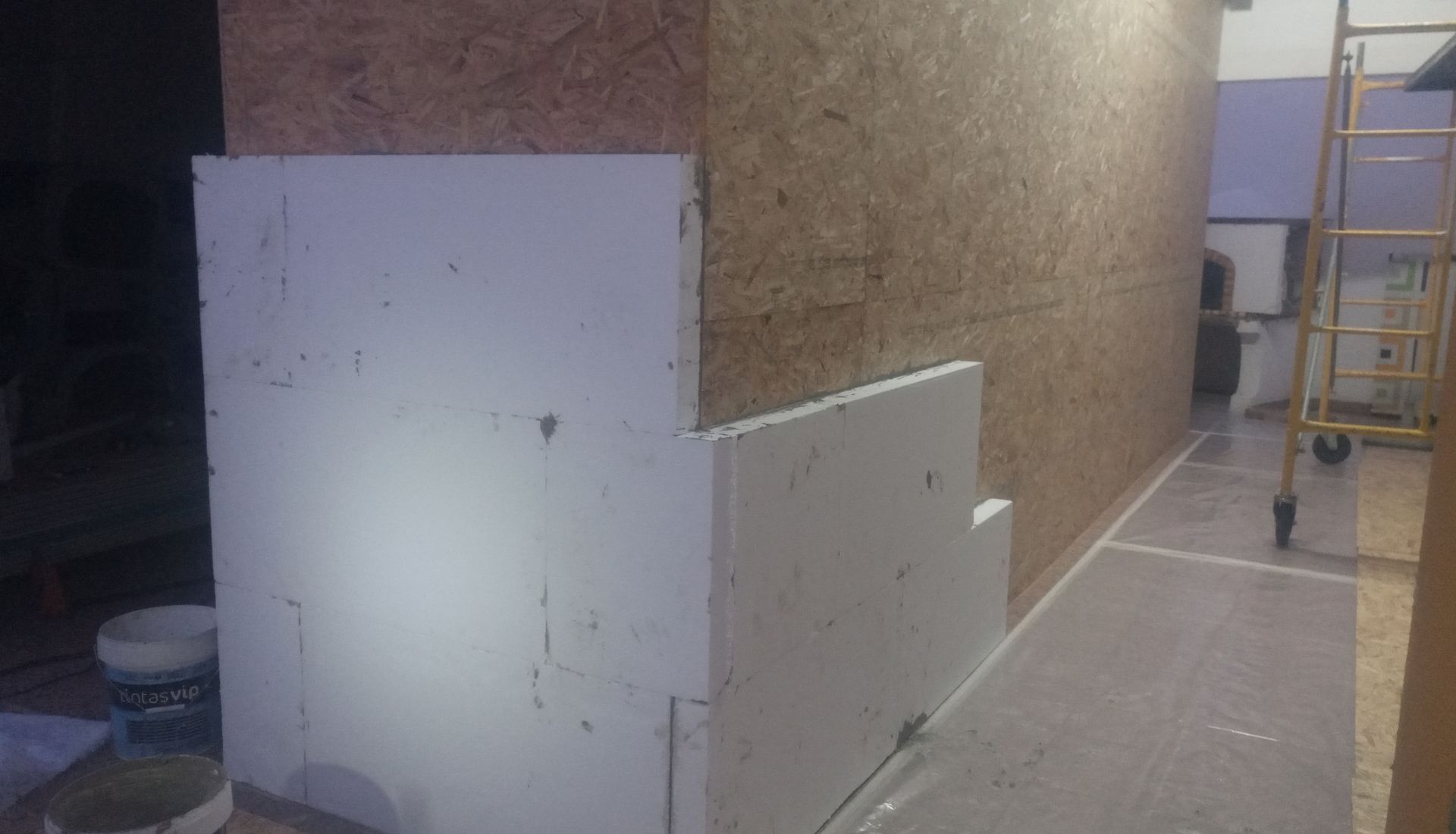 Placas de isolamento de espuma branca fixadas em uma parede de madeira compensada.