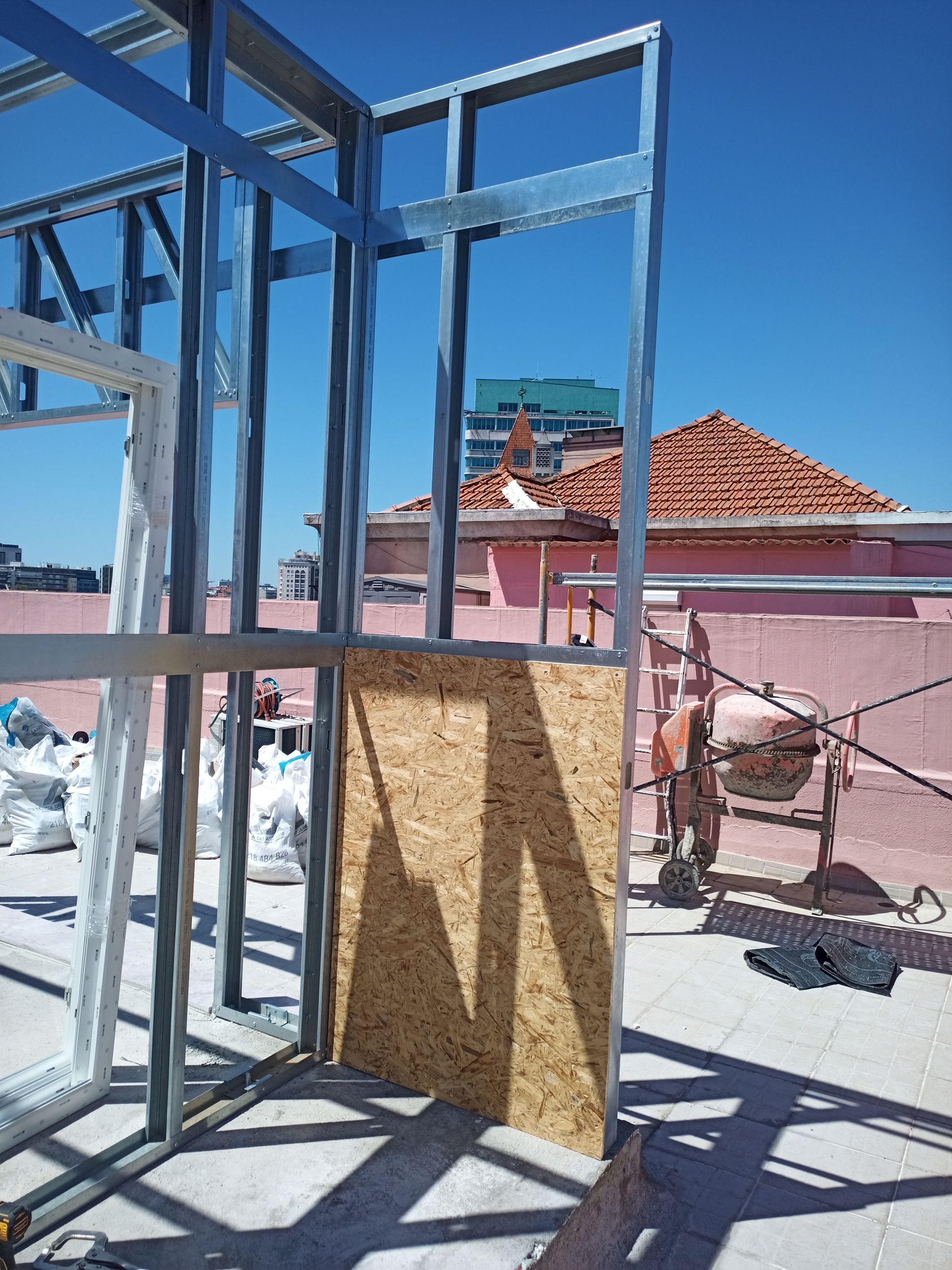 Estrutura metálica para um edifício com painéis de madeira. Construção em um telhado ensolarado.