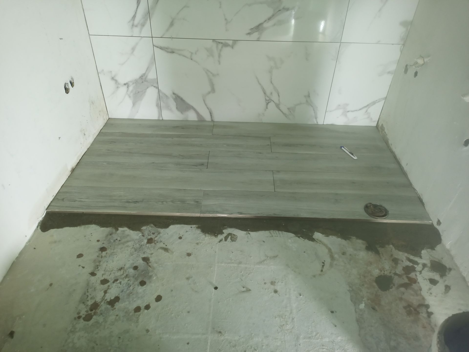 Banheiro em construção; piso revestido com azulejos, paredes parcialmente azulejadas; ambiente de construção.