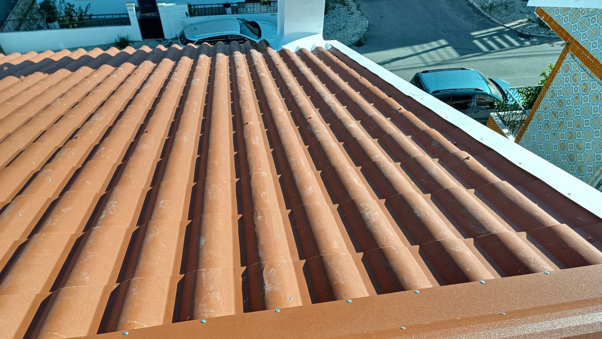Telhado de telha de barro vermelha com cumeeiras paralelas, exposto ao sol.