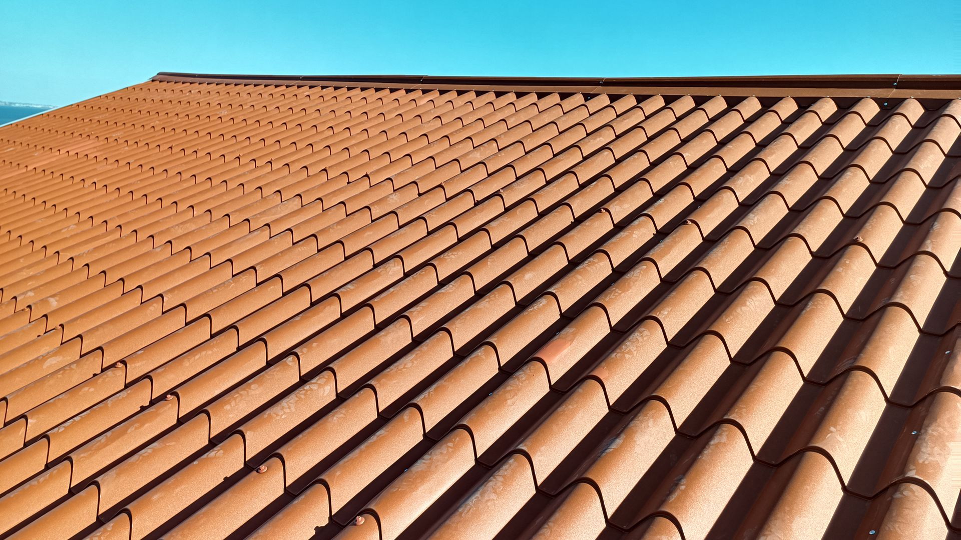 Telhado de telhas de terracota vermelhas sob um céu azul límpido.