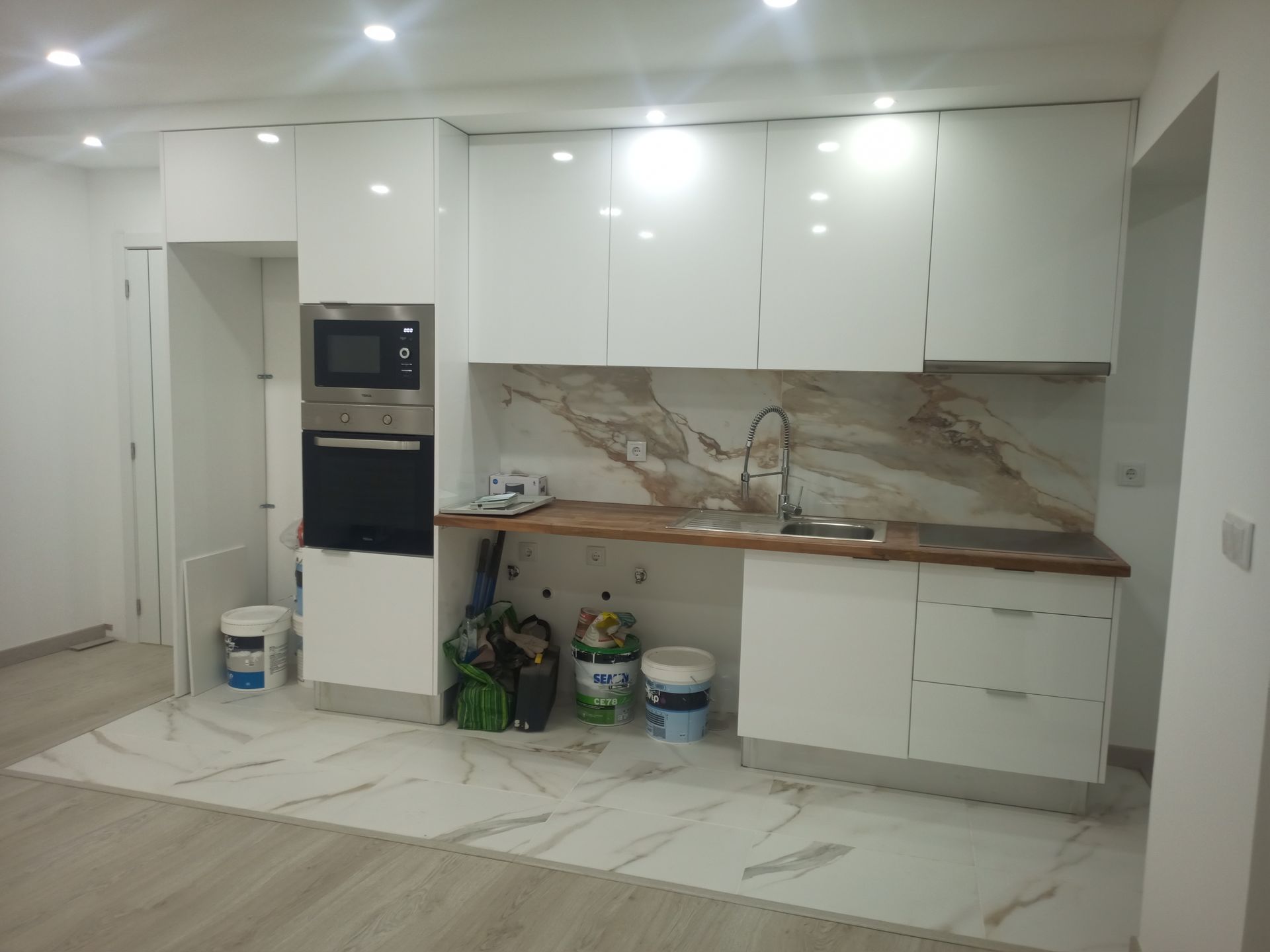 Cozinha moderna branca com backsplash, armários e eletrodomésticos em mármore.