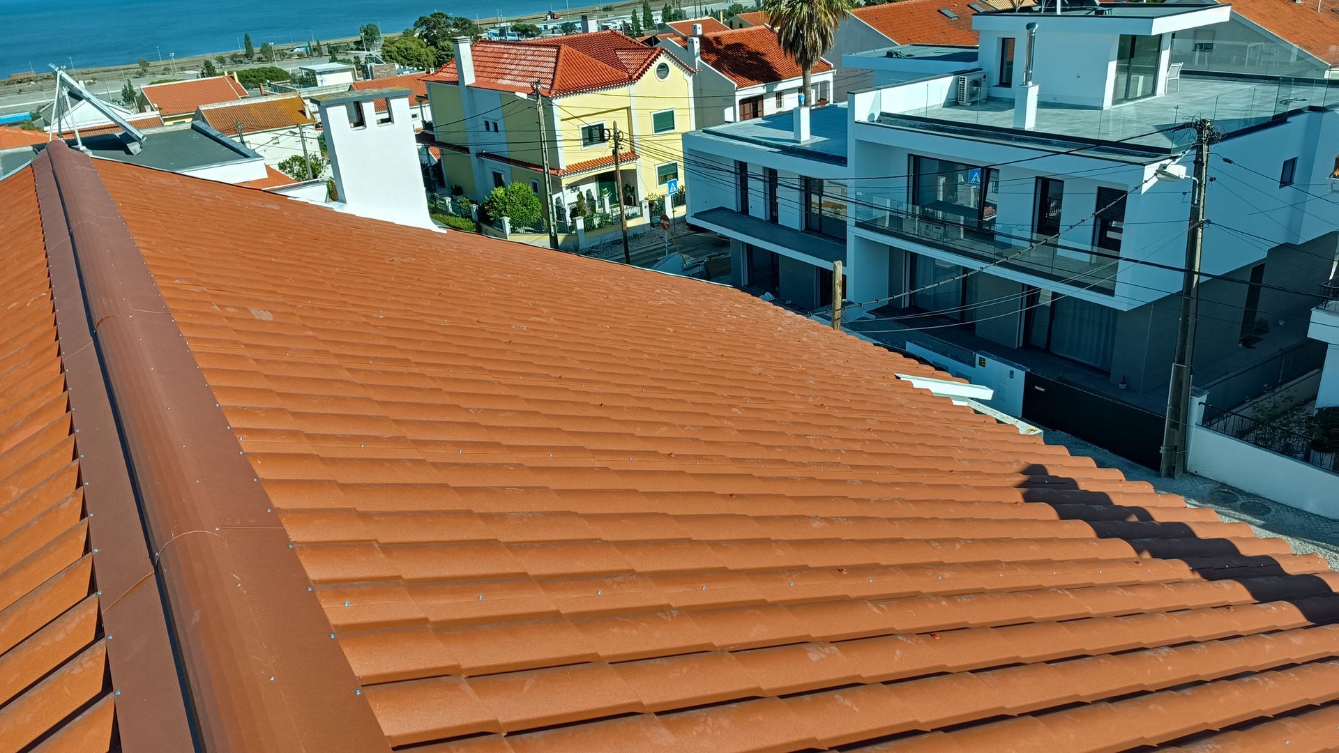 Telhado de telha vermelha com paisagem urbana ao fundo.