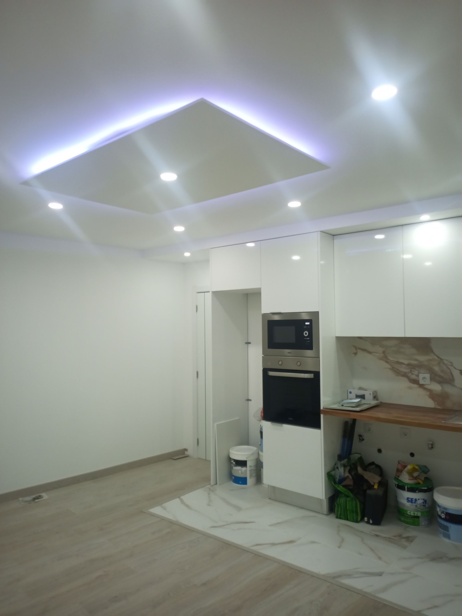 Cozinha moderna branca com teto rebaixado e eletrodomésticos embutidos.