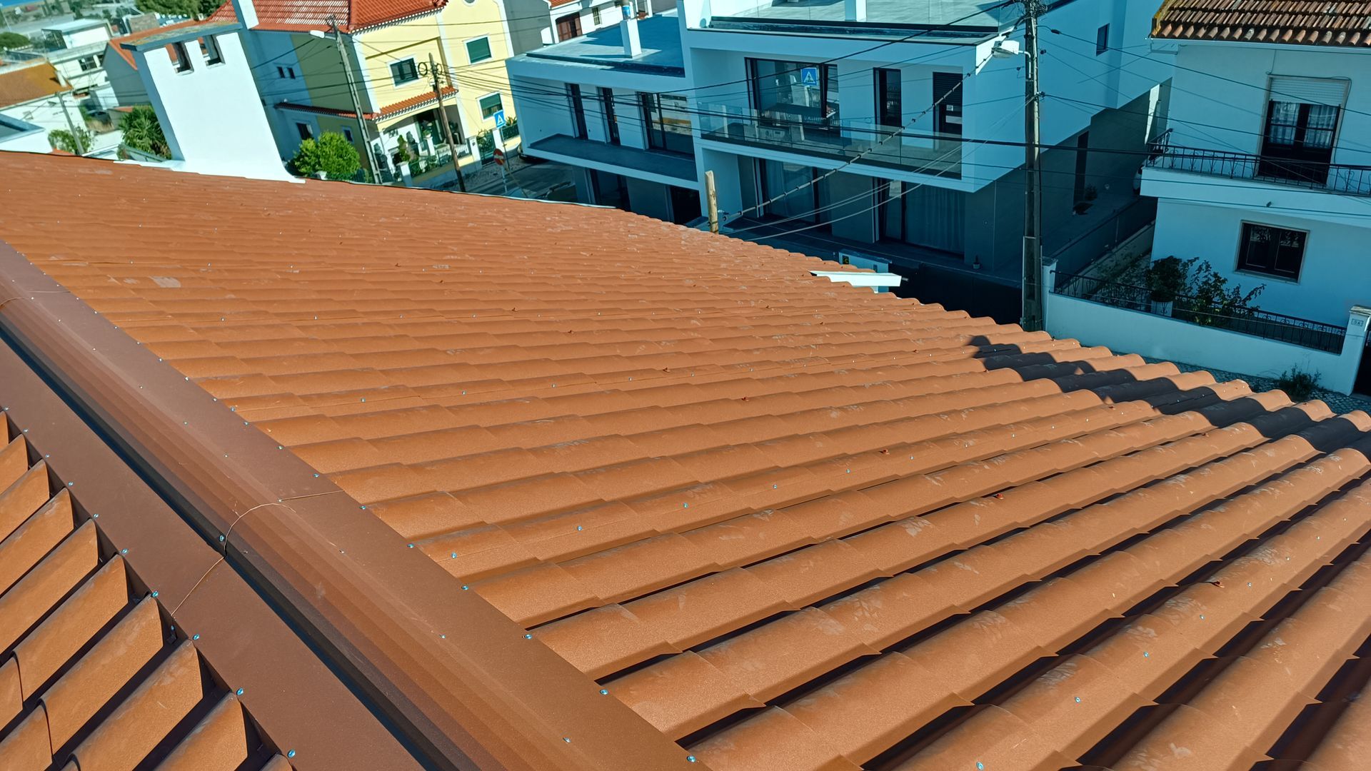 Telhado de telha de terracota marrom de um edifício cercado por construções brancas.