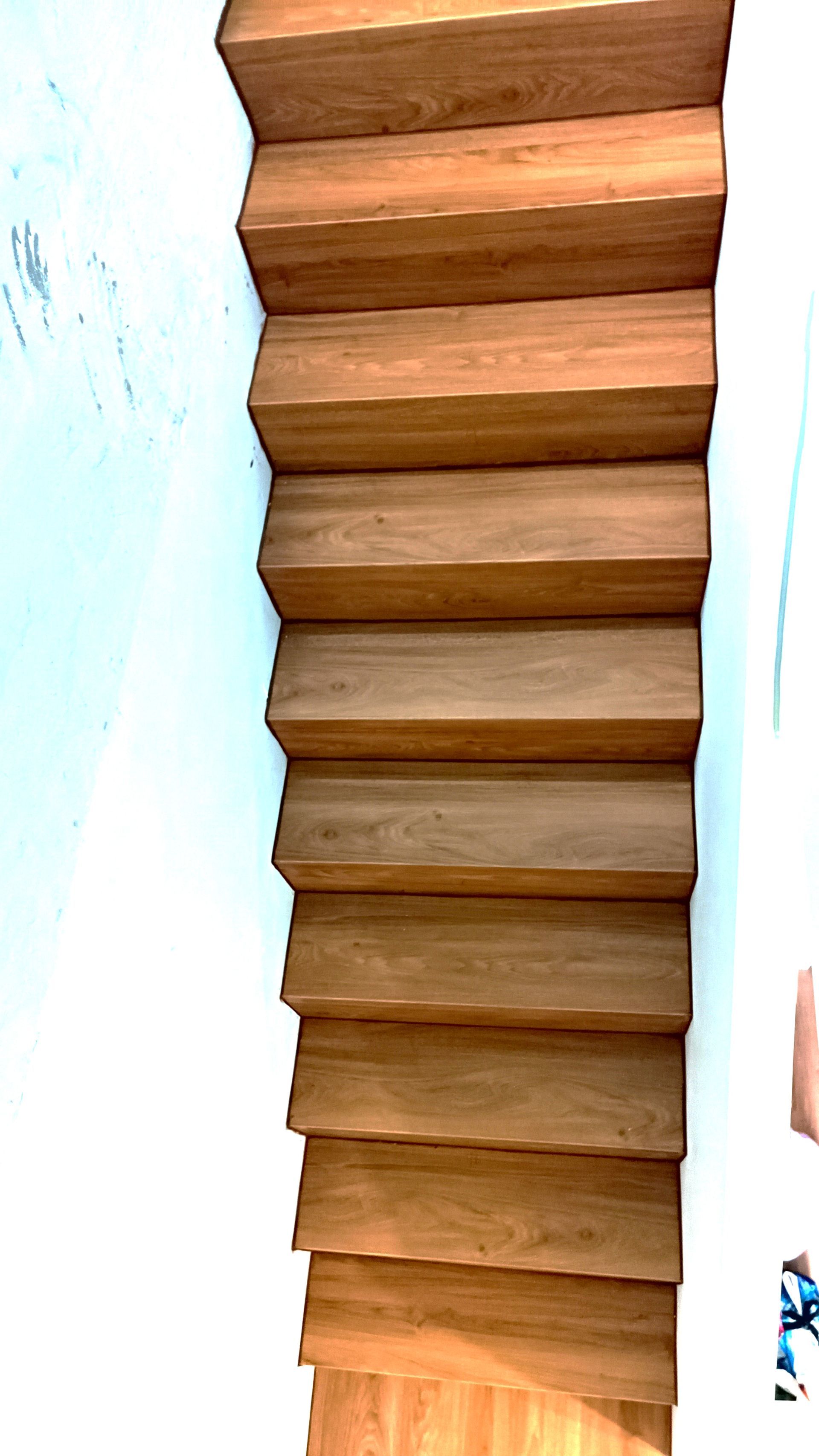 Escada de madeira contra uma parede branca.