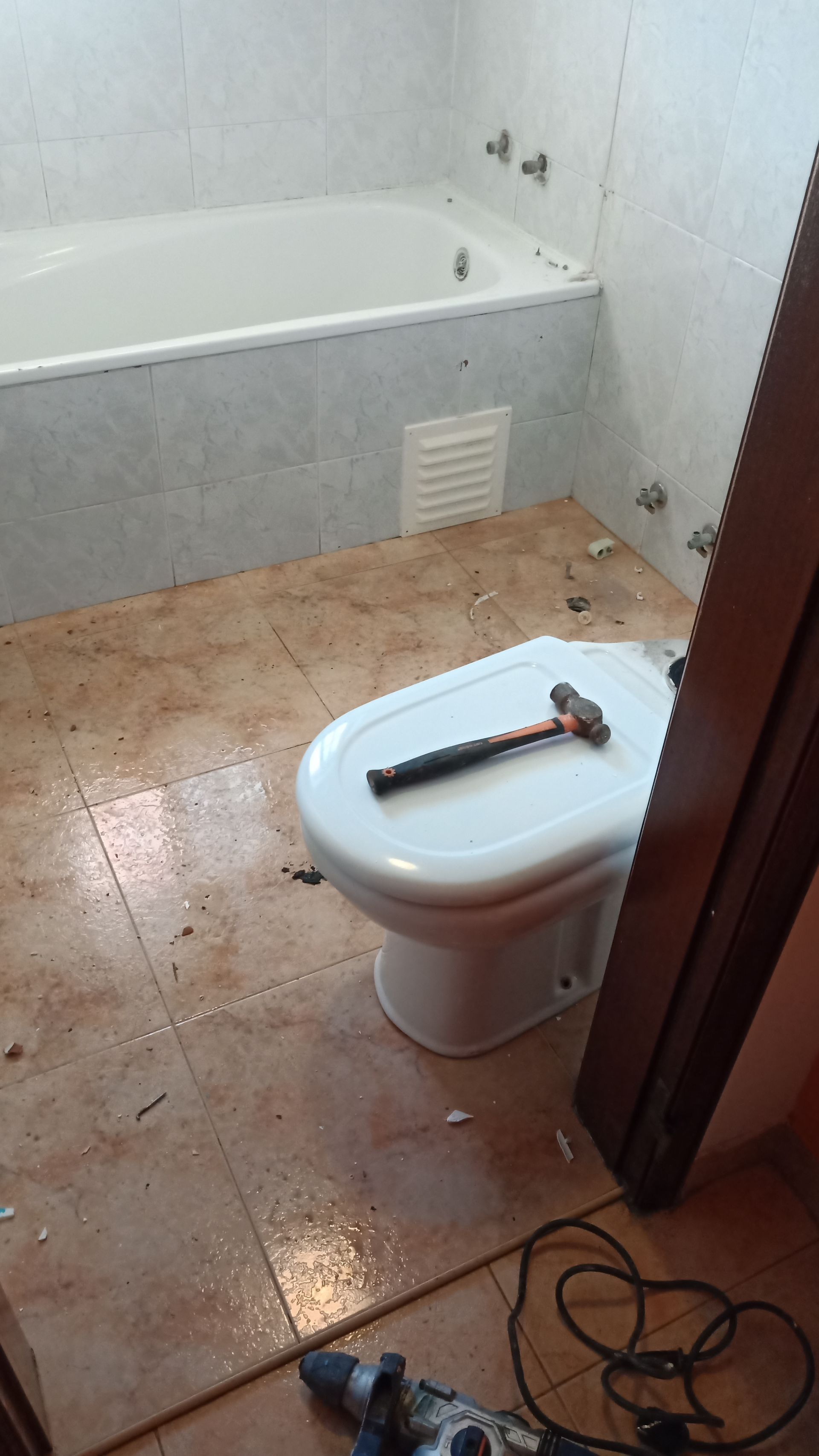 Reforma do banheiro em andamento: vaso sanitário com acabamento improvisado, piso aparente, banheira.