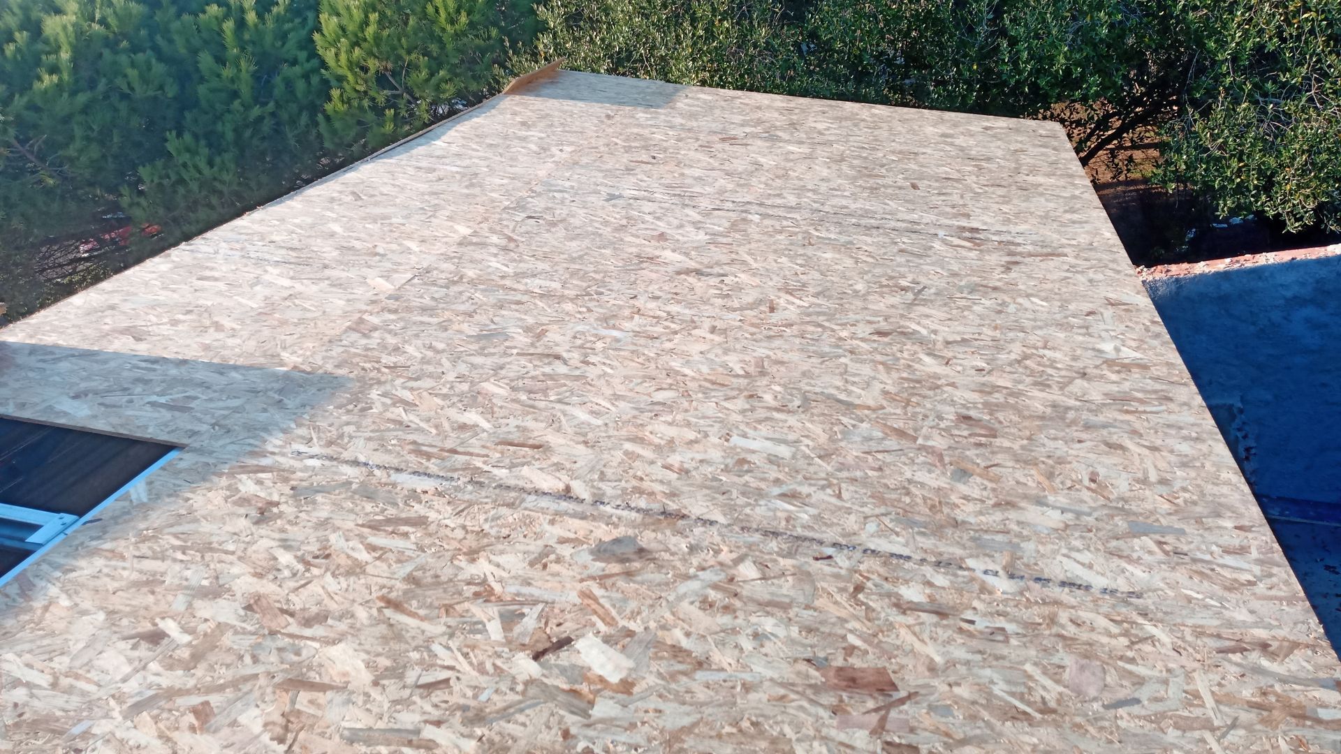 Placas de revestimento de telhado em OSB instaladas em um edifício, prontas para receber o telhado.