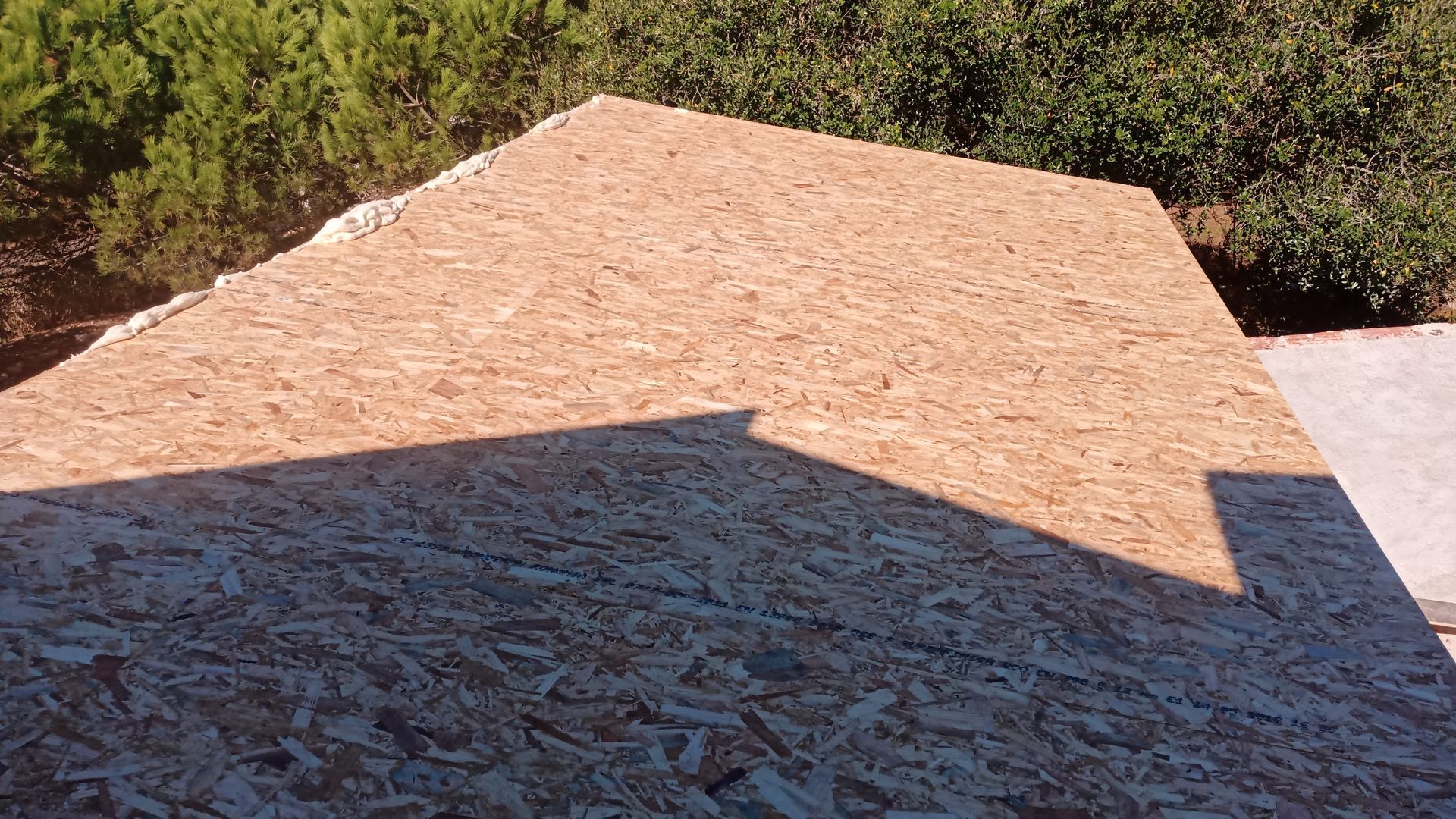 Revestimento de OSB em telhado de duas águas, exposto à luz solar direta.