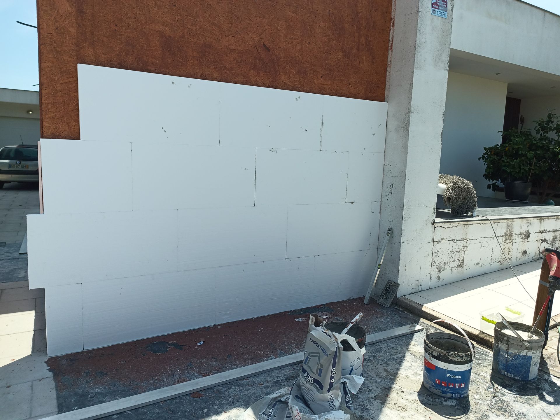 Parede em construção com painéis de isolamento branco, parede marrom e ferramentas.