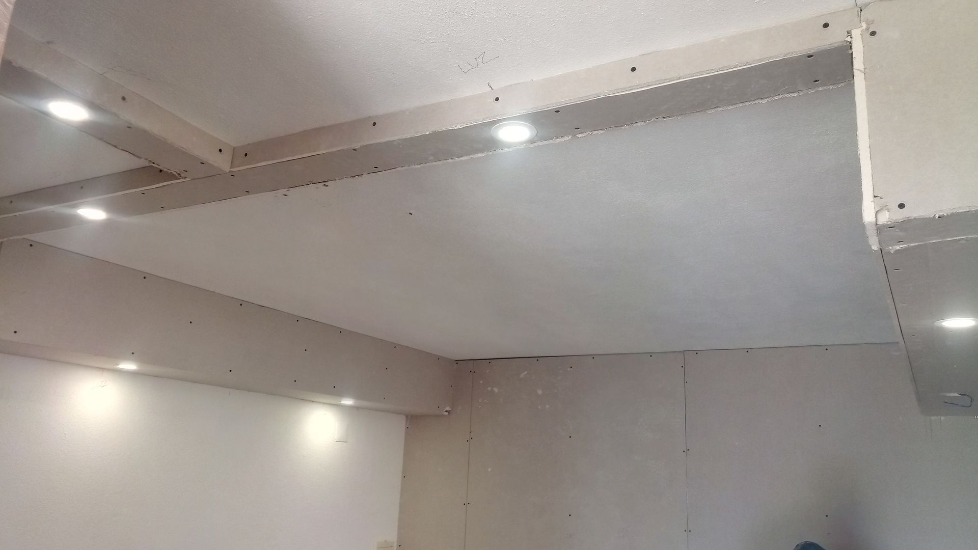 Teto interno com iluminação embutida e drywall aparente.
