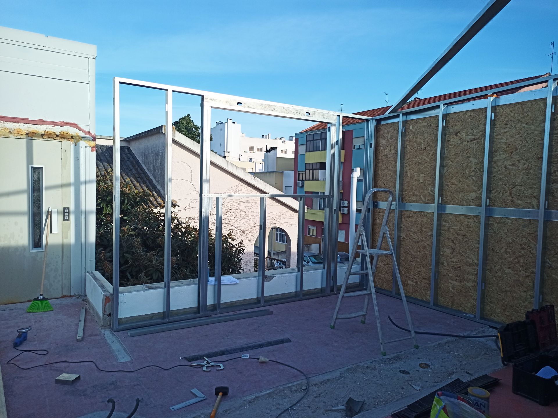 Construção de uma parede com estrutura metálica em um telhado, com instalação de placas de isolamento.