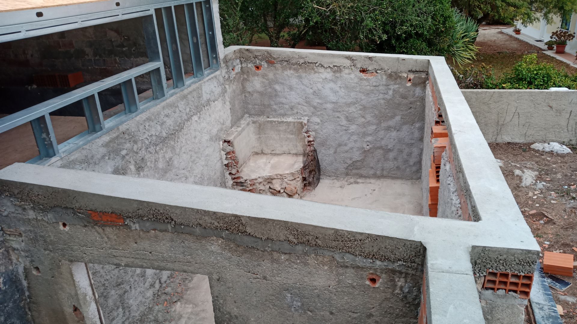 Estrutura de concreto em construção, com armação metálica aparente, alvenaria e elemento embutido.