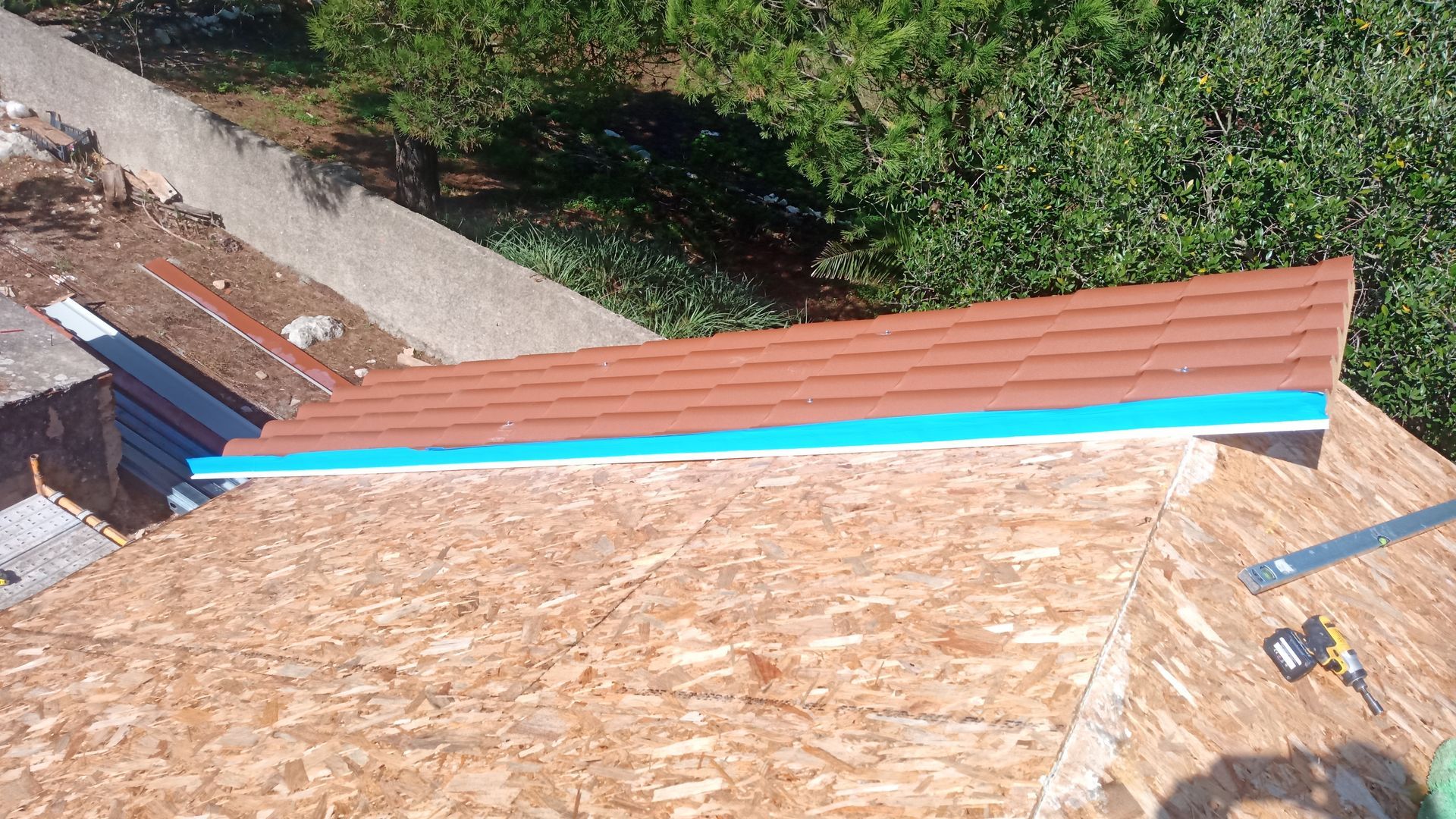 Construção do telhado: Telhas marrons, detalhes em azul e revestimento de madeira aparente.