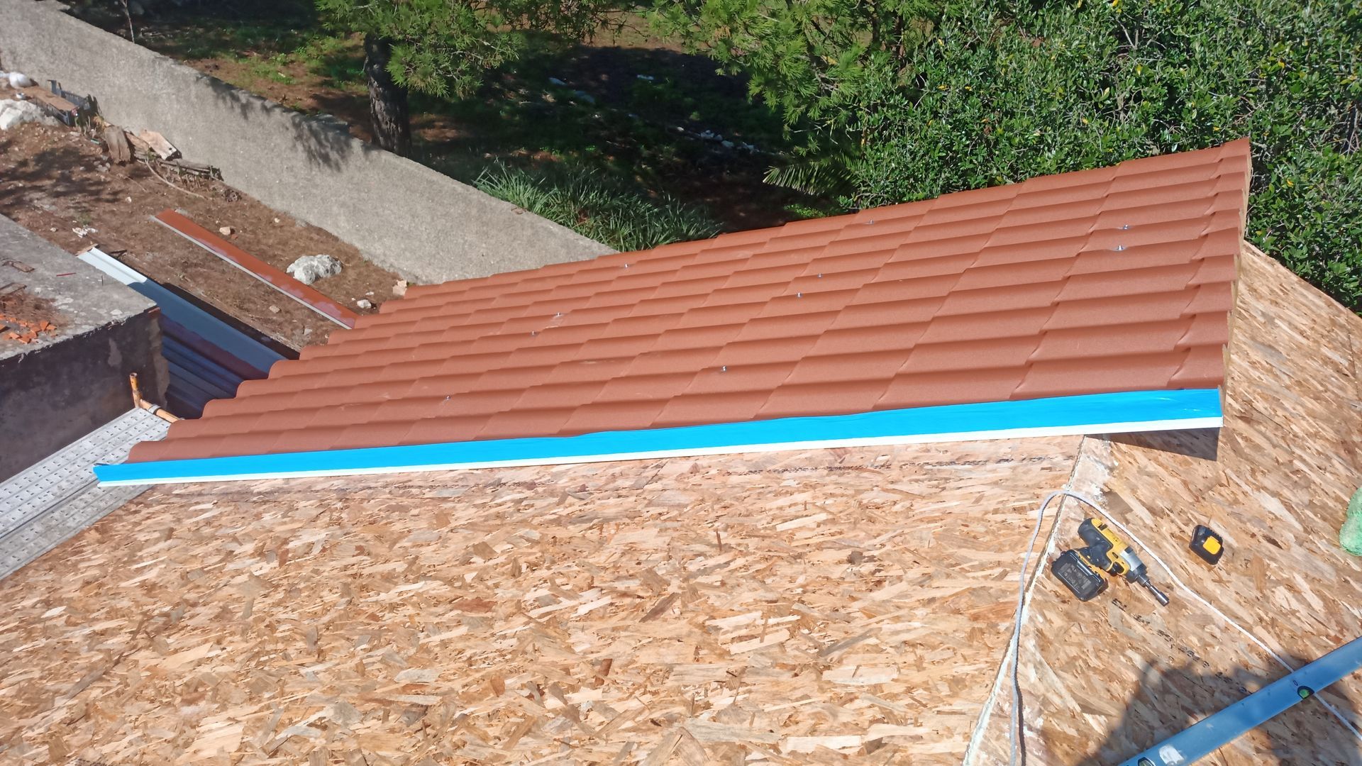 Telhado novo de telhas de terracota instalado sobre estrutura de madeira, com rufo azul visível.