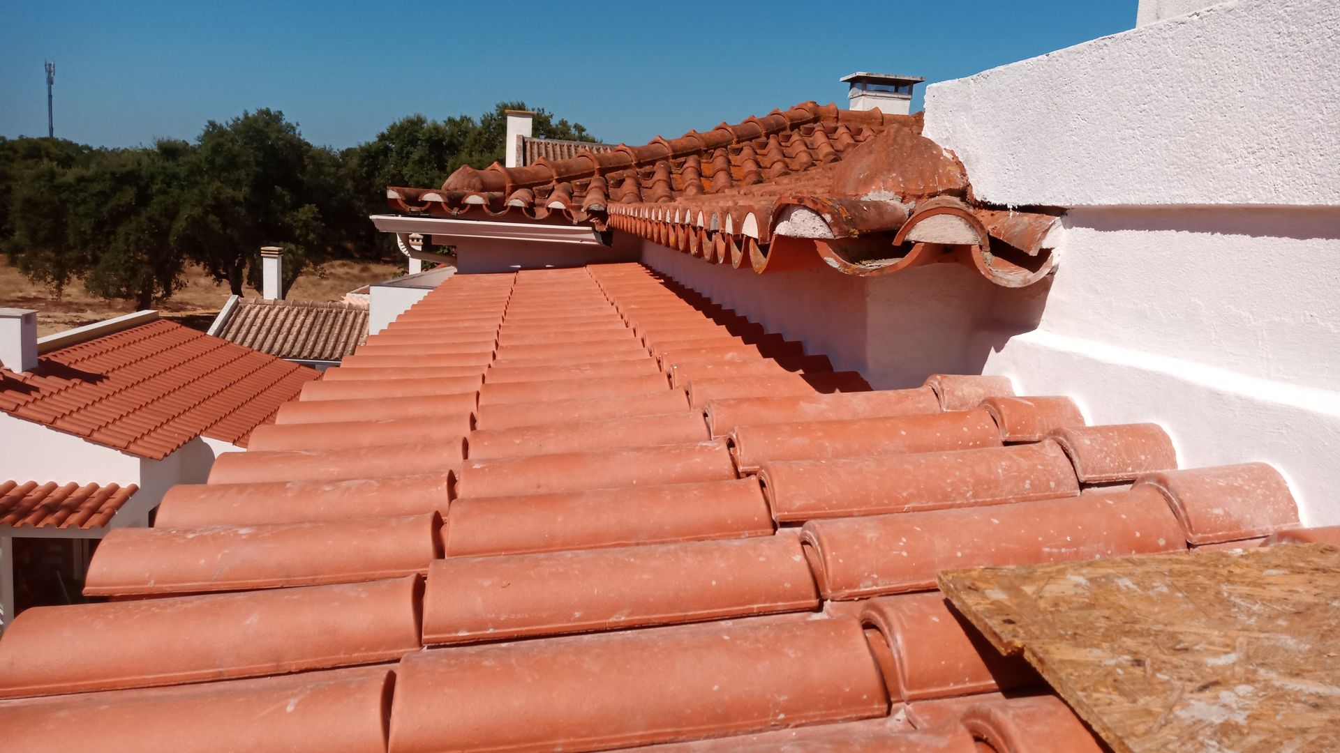 Telhado de telha de barro em um prédio branco, dia ensolarado.