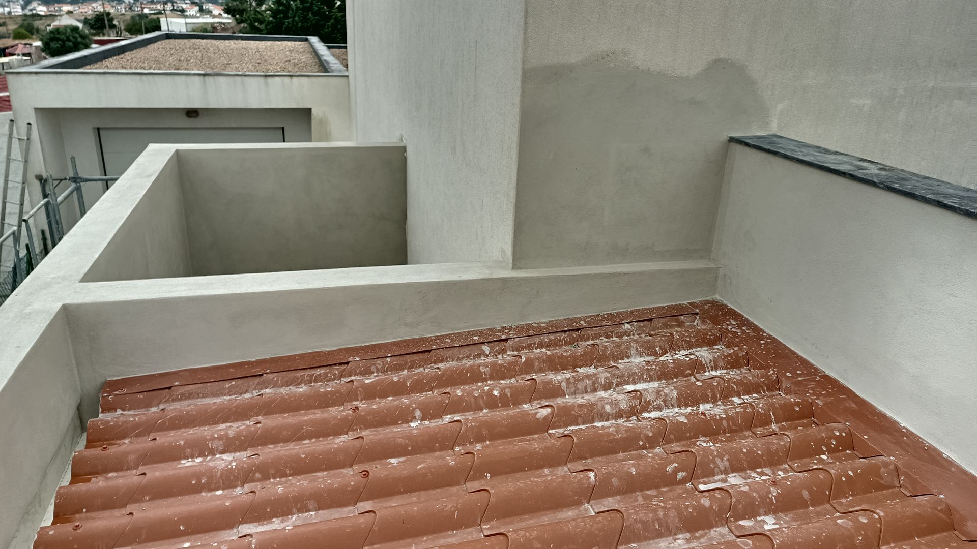 Telhado com telhas onduladas vermelhas, paredes cor creme e uma área recuada; exterior do edifício.