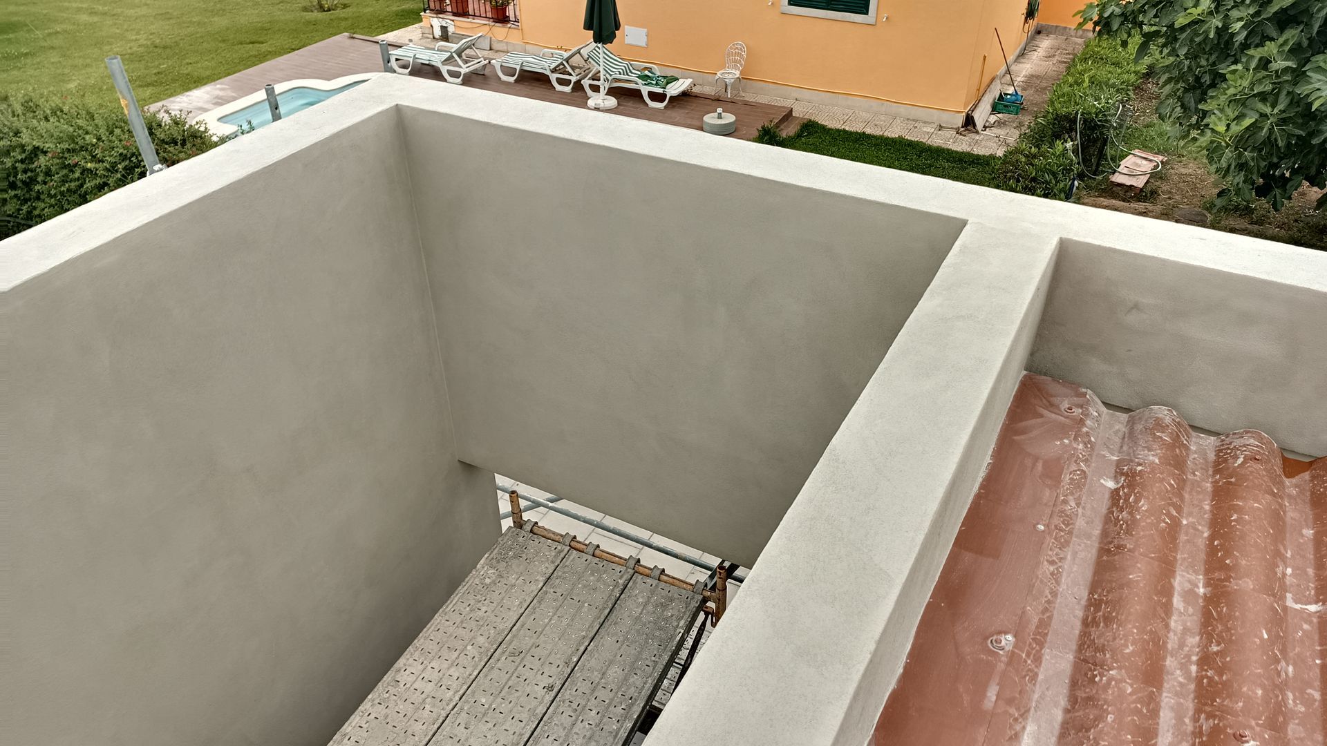 Vista exterior de um edifício com uma secção recentemente rebocada, sendo possível observar andaimes no interior de uma parede.