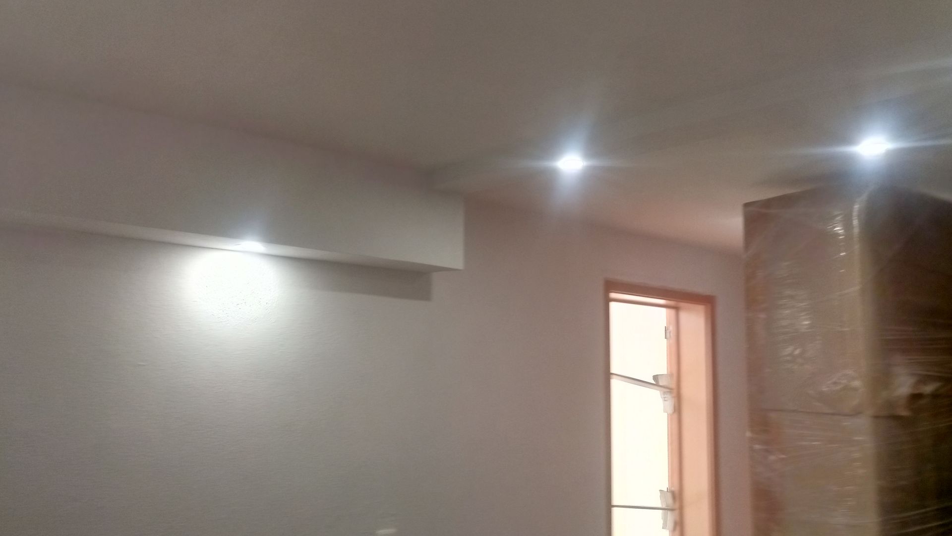 Interior branco com luzes embutidas; ar condicionado acima da parede.