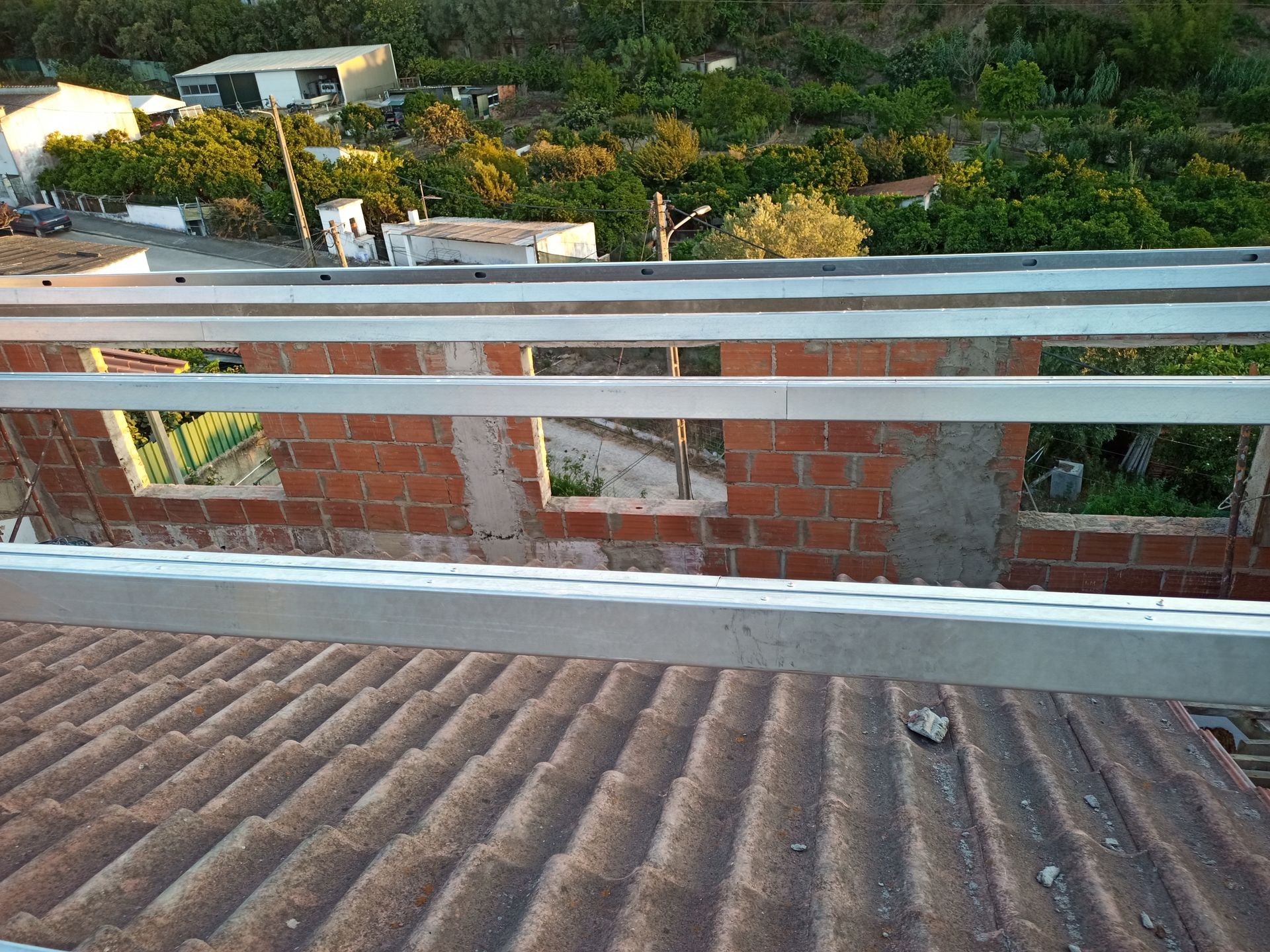 Canteiro de obras: paredes de tijolos sob o telhado com vigas metálicas horizontais.