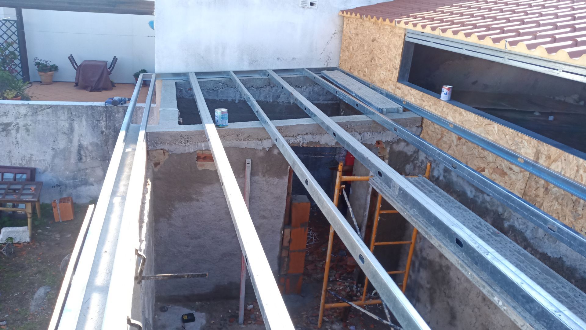 Estrutura metálica preparada para o teto de uma estrutura externa; construção em andamento.