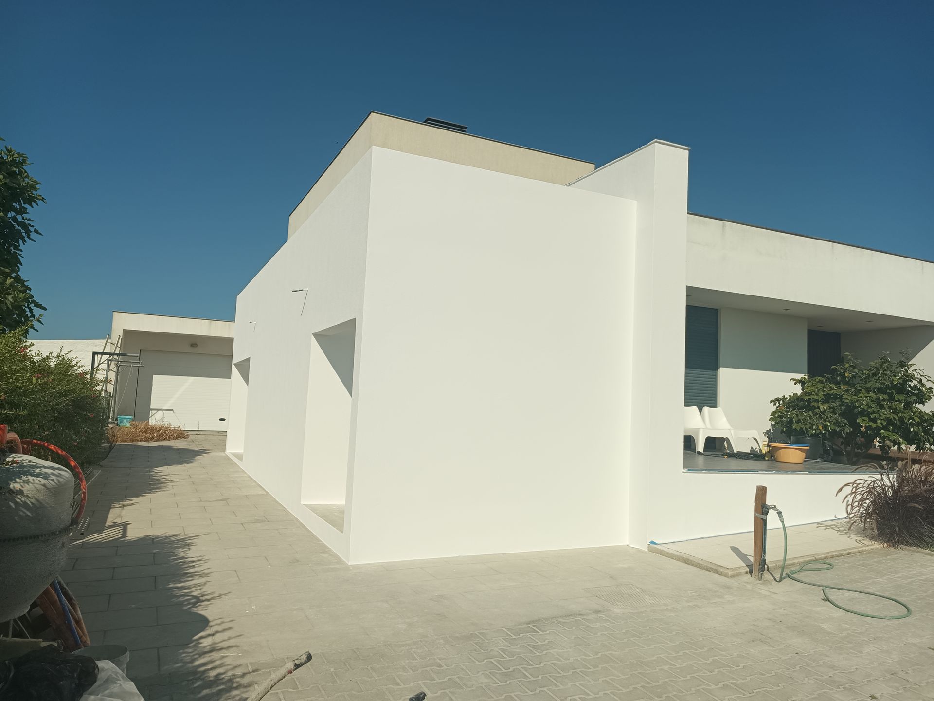 Prédio moderno branco com caminho de concreto e céu azul claro.