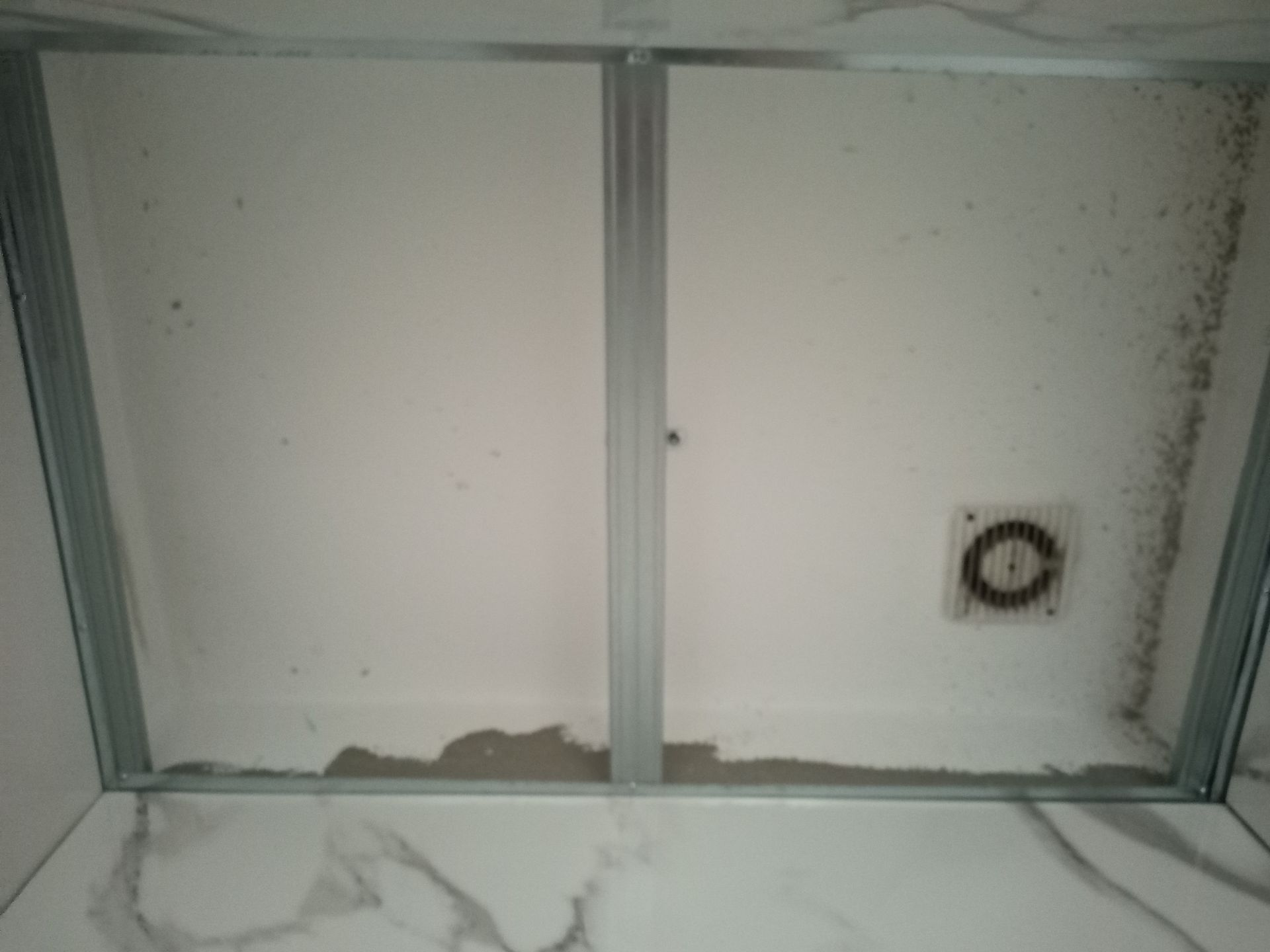 Teto branco em construção, estrutura metálica, ventilador de exaustão, manchas escuras.