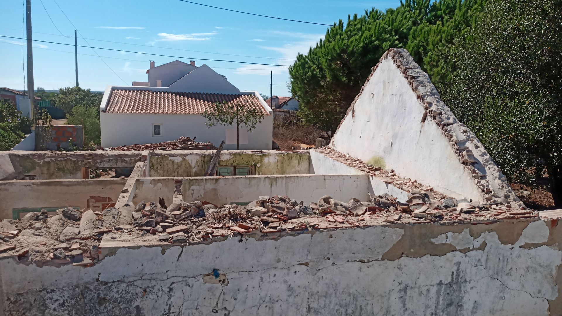 Restos de um prédio de concreto demolido, entulho nas paredes, outras estruturas visíveis ao fundo.