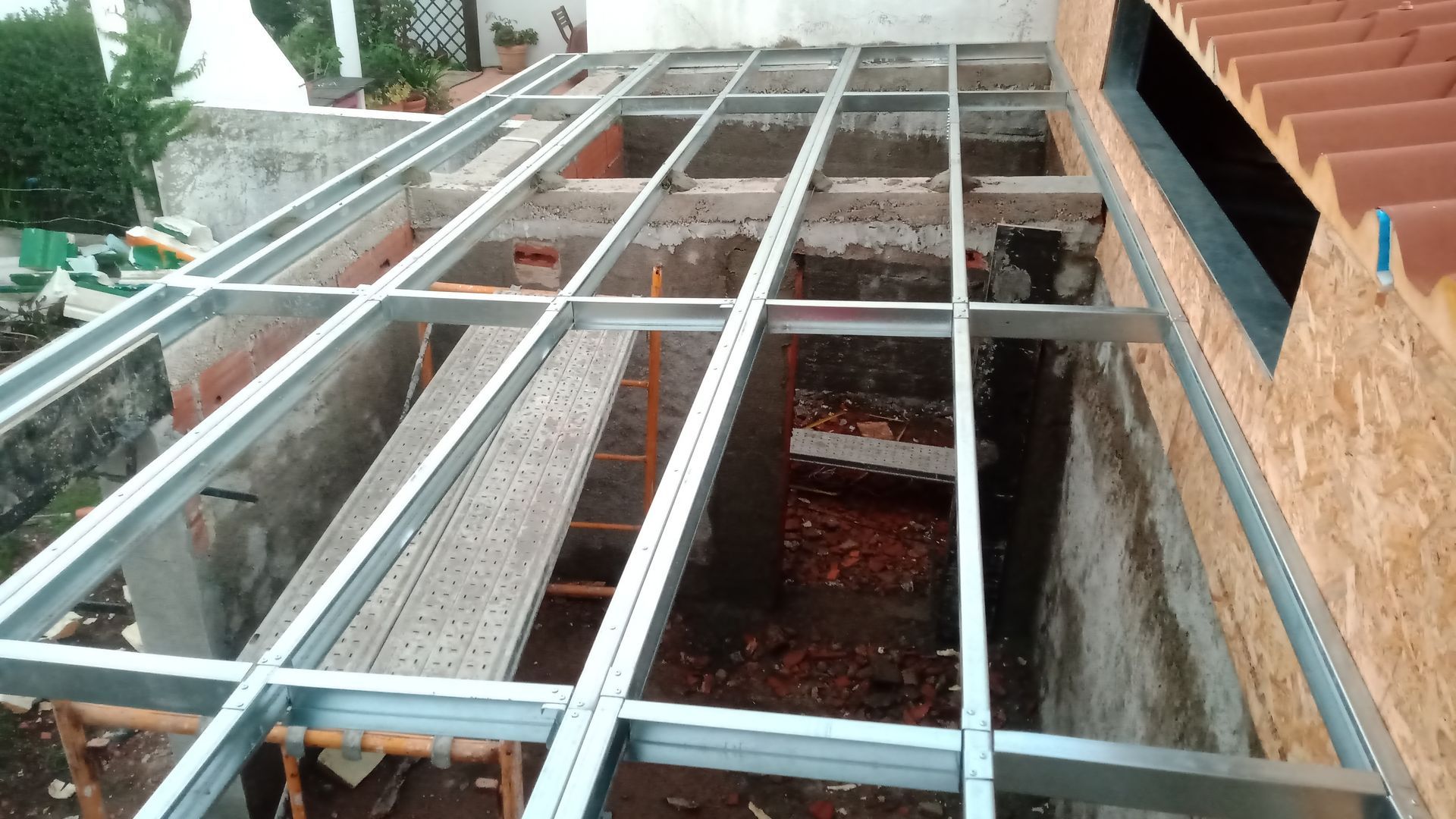 Estrutura metálica para um telhado em construção. A estrutura está localizada sobre uma área parcialmente demolida.