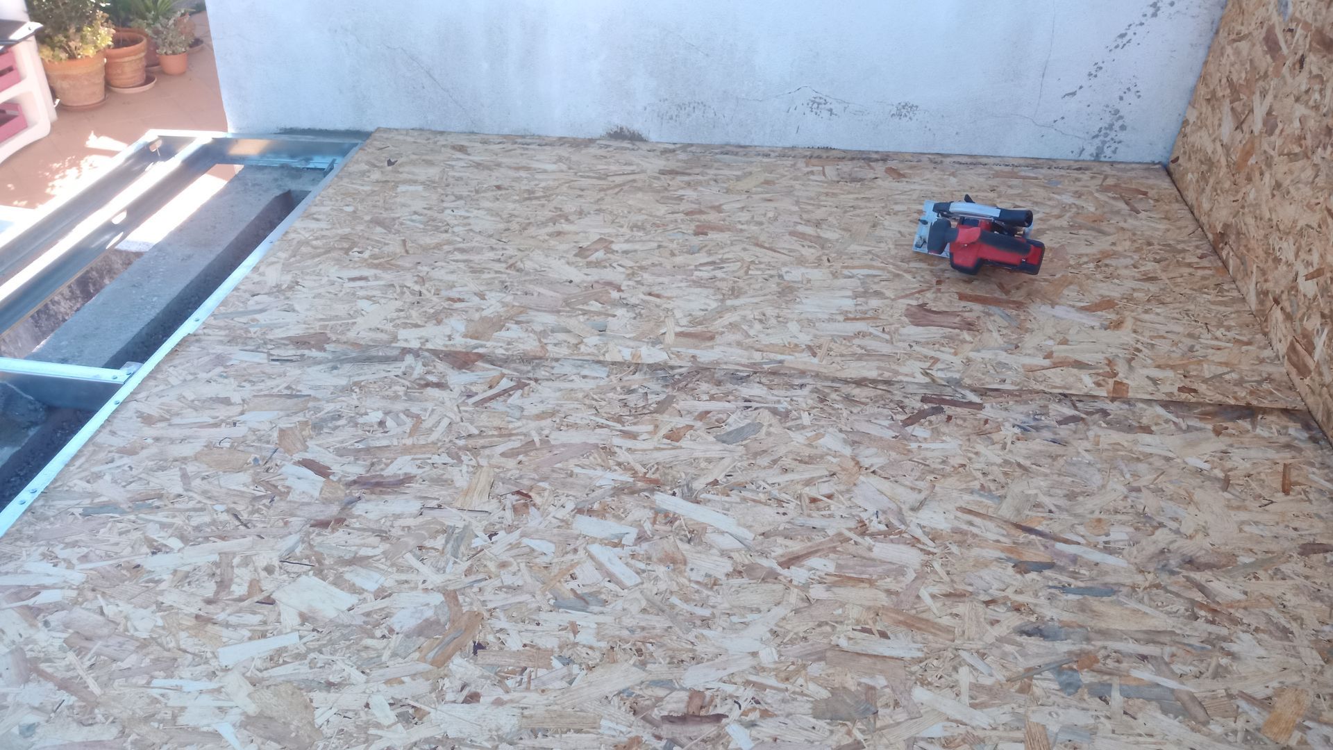 Subpiso de OSB instalado em um deck, com uma ferramenta elétrica vermelha.