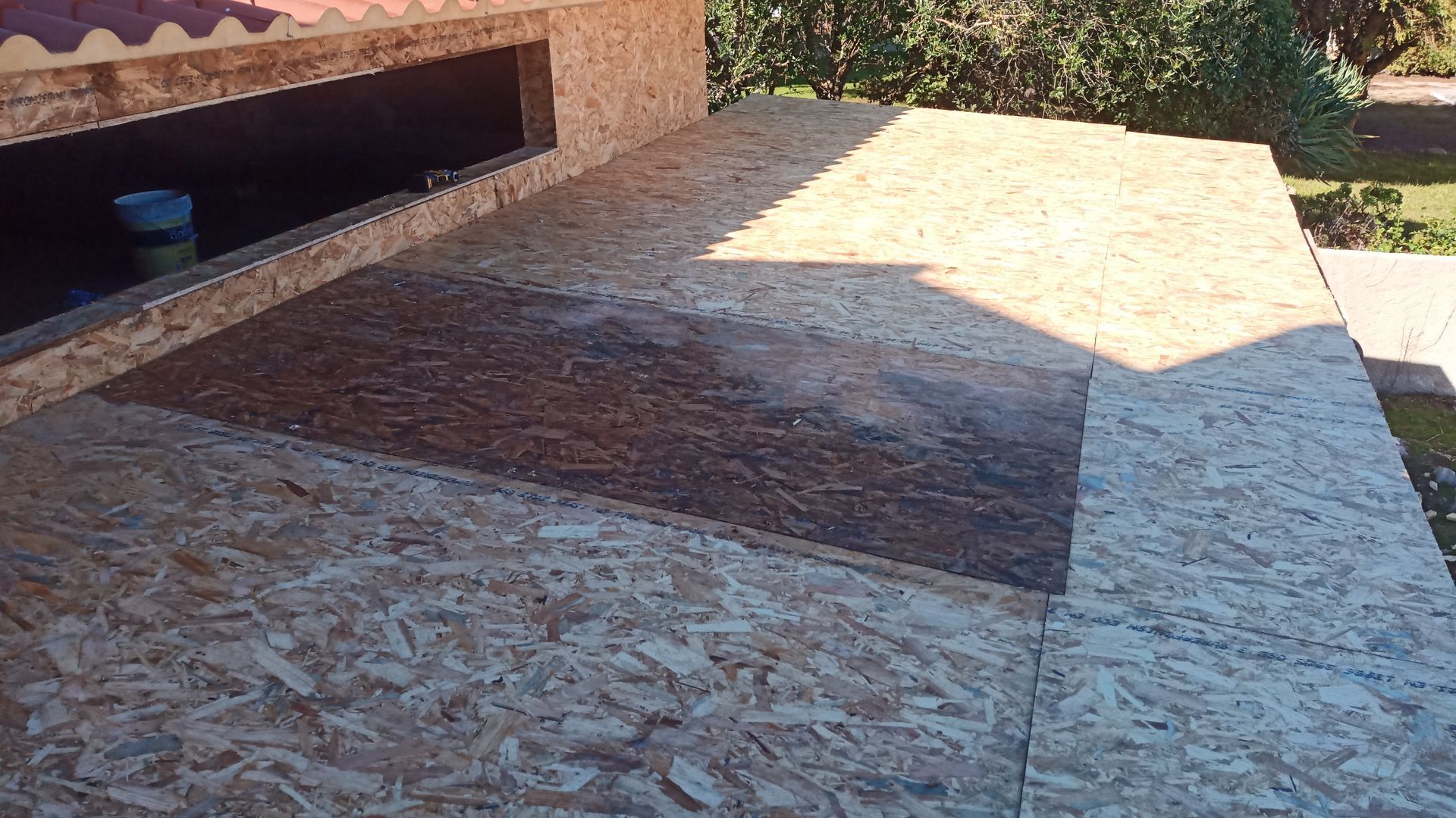 Revestimento de OSB em um telhado com uma seção retangular mais escura.