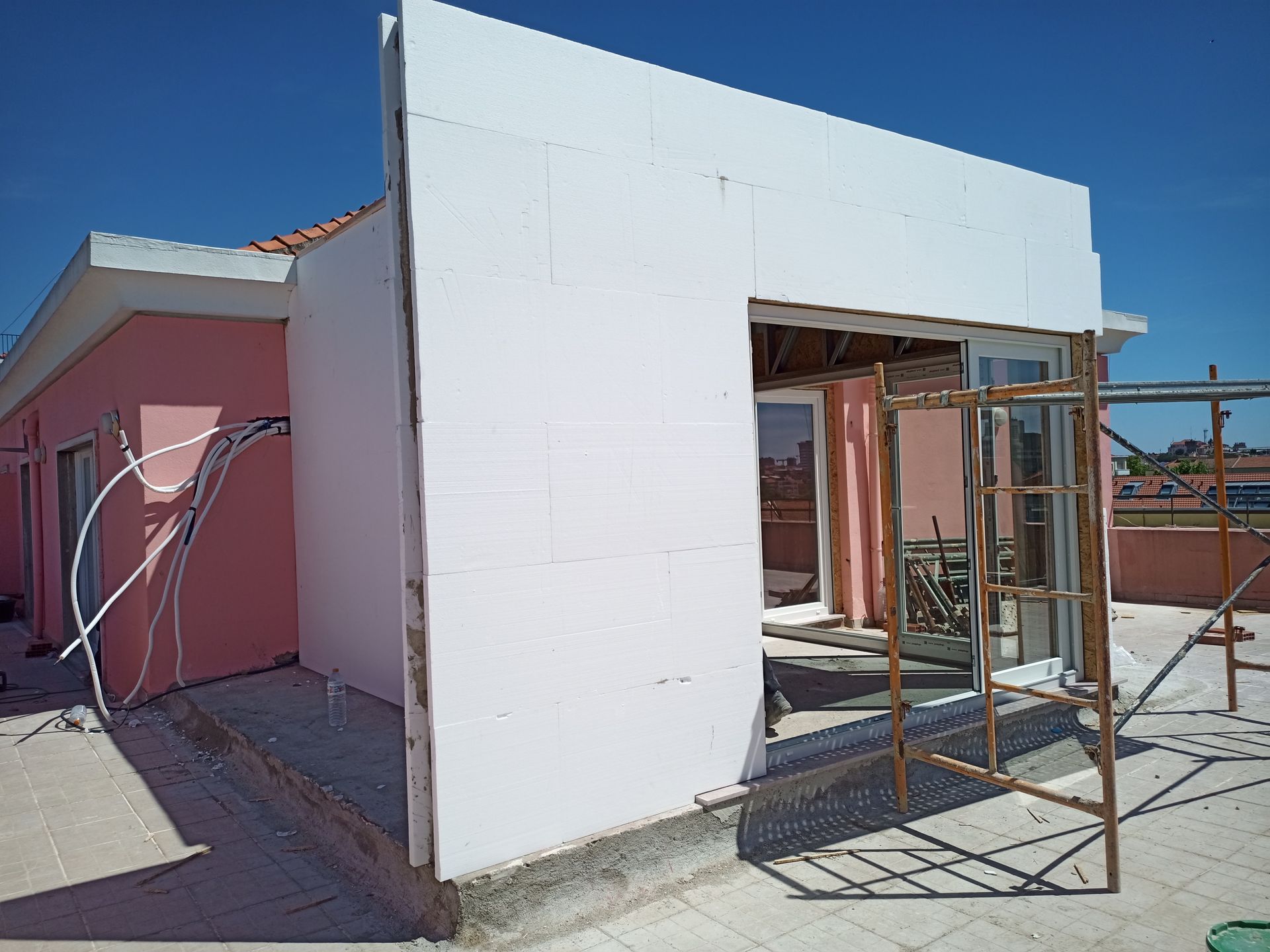 Exterior de prédio em construção; isolamento de espuma branca em um prédio rosa contra um céu azul.