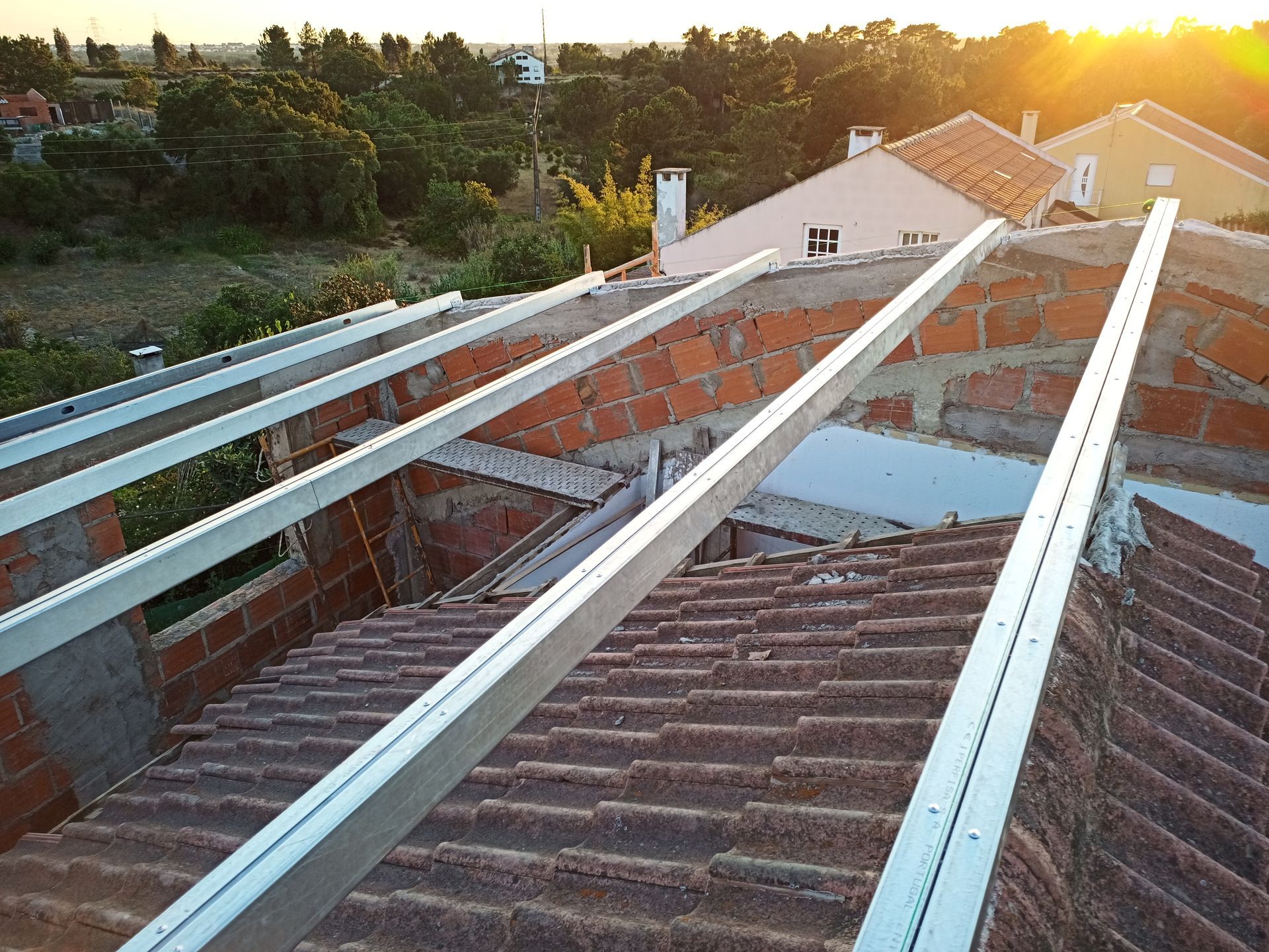 Telhado com trilhos metálicos para instalação de painéis solares, tijolos, telhas e luz solar.