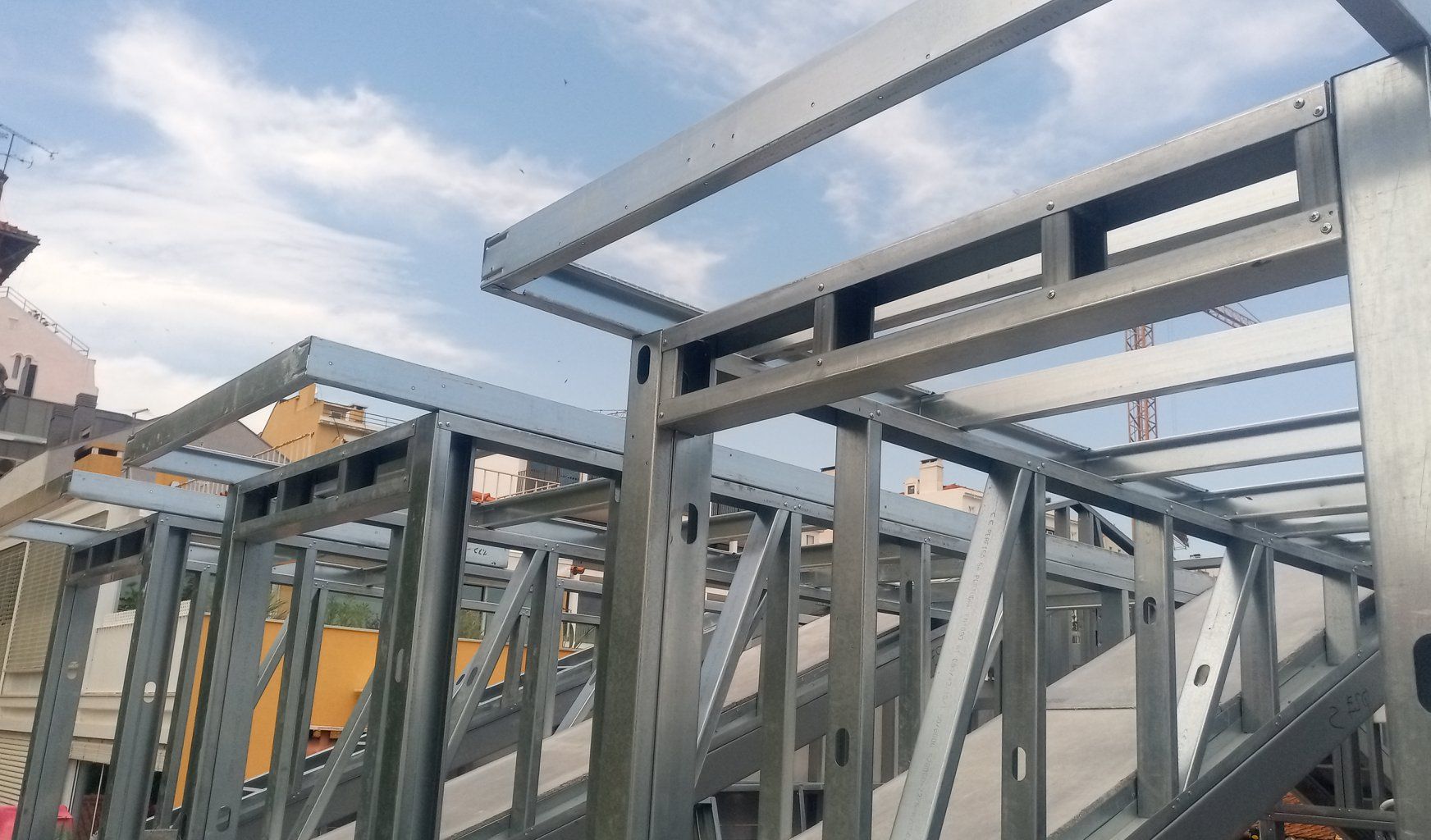 Estrutura metálica de um edifício em construção, contra um céu nublado.