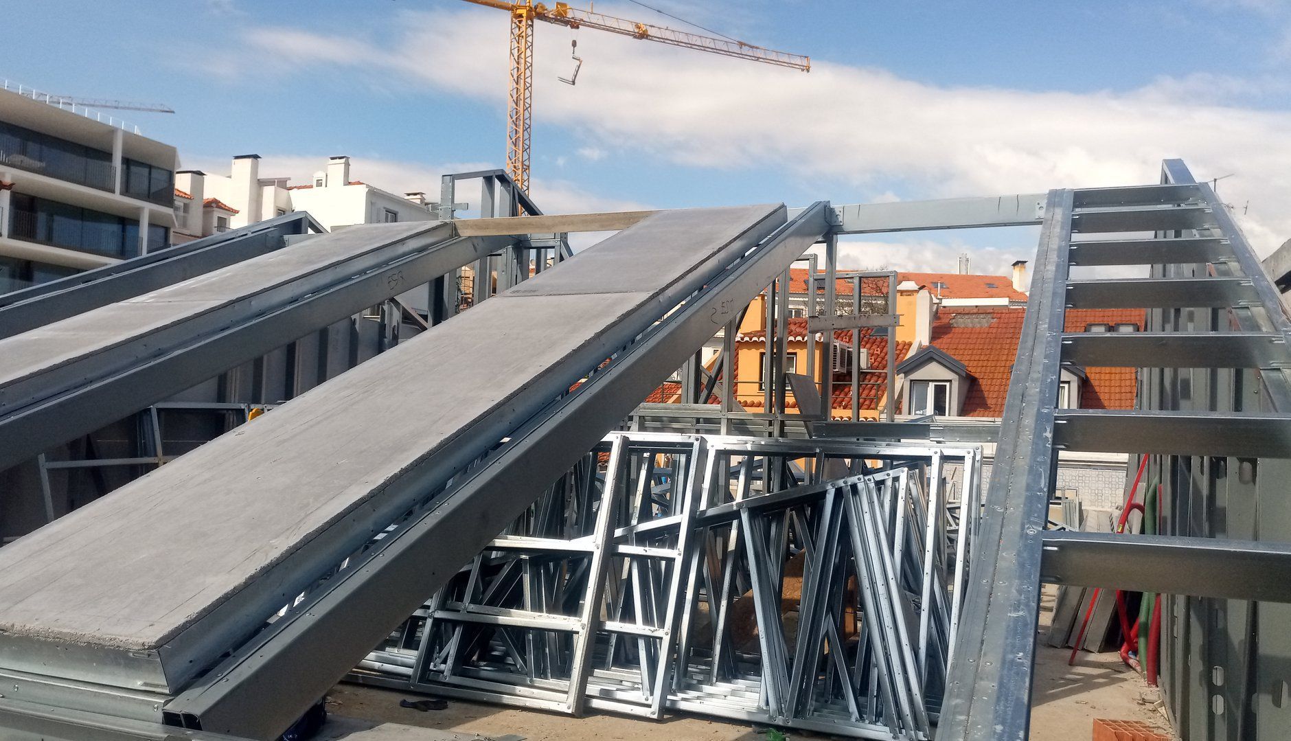Estrutura metálica do telhado em construção, com um guindaste ao fundo.