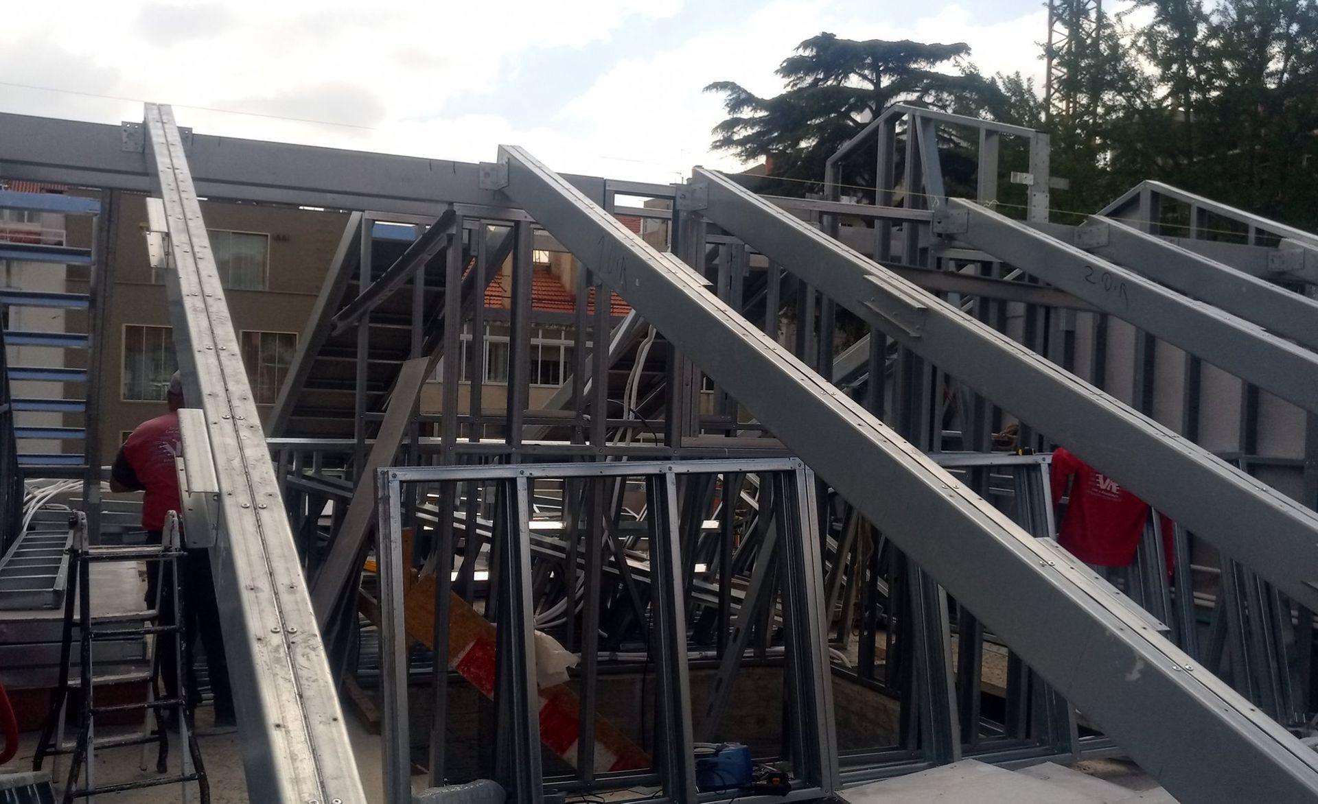 Construção de uma estrutura de aço para o telhado, com operários presentes.