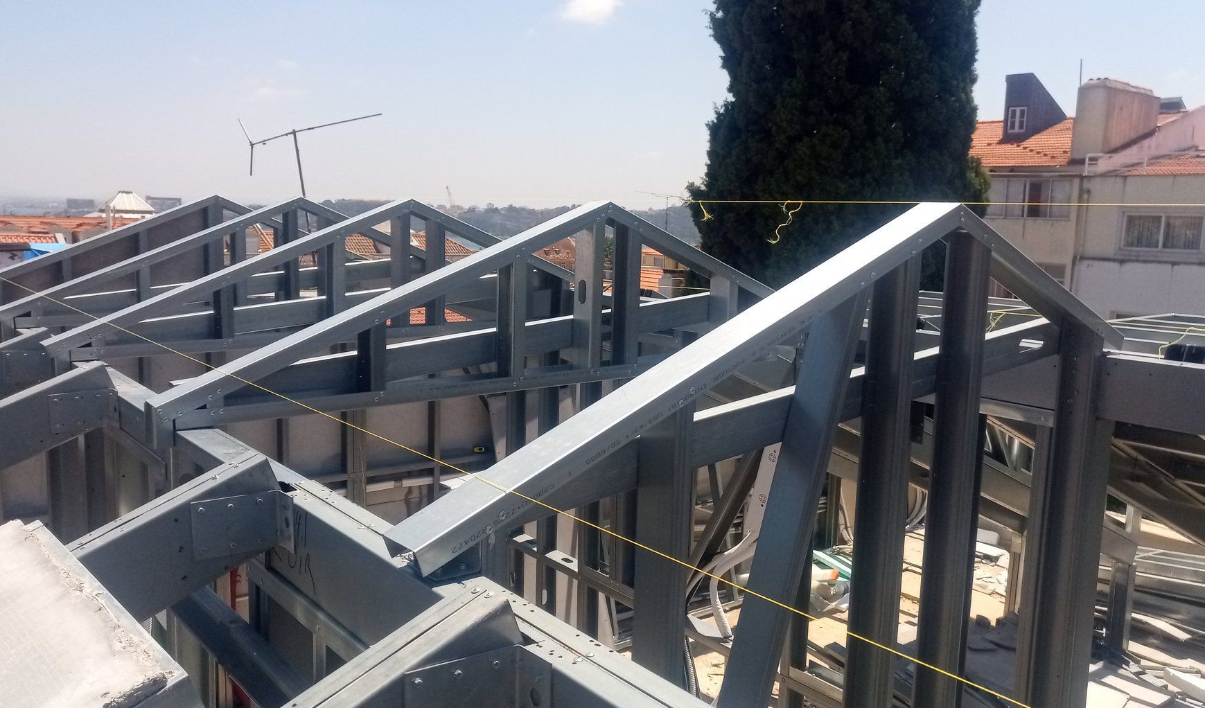 Estrutura metálica do telhado de um edifício, com céu limpo ao fundo.