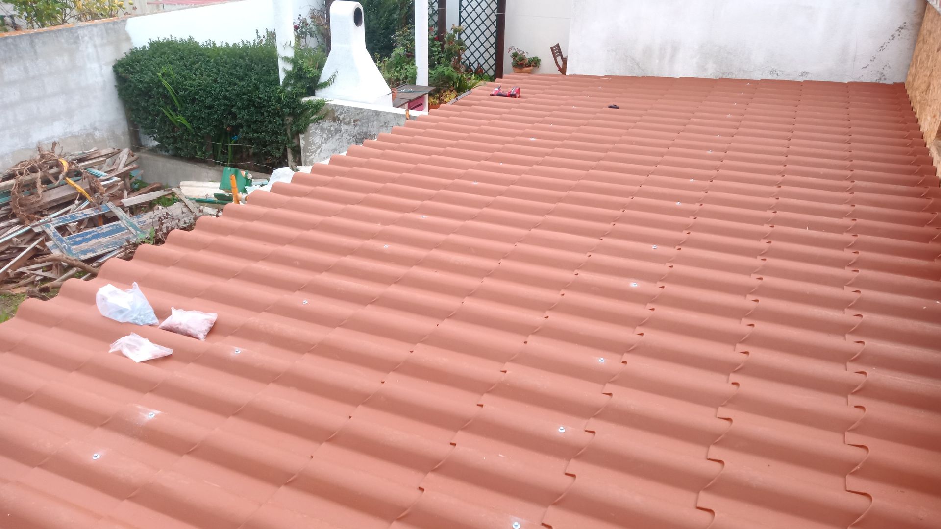 Telhado de zinco vermelho com jardim ao fundo.