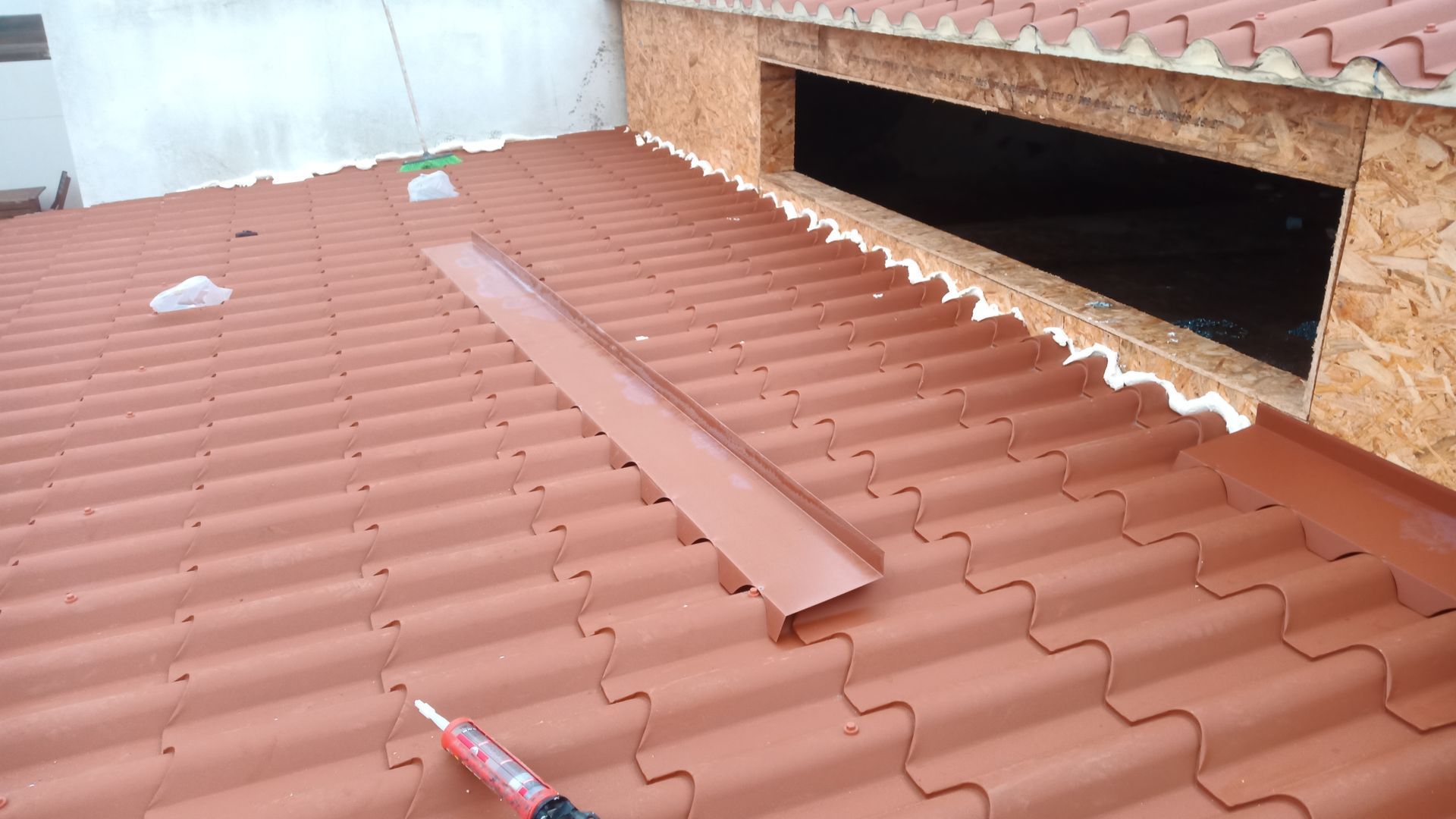Telhado de zinco vermelho com abertura retangular e revestimento metálico.